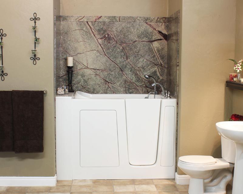 White walk-in tub with door, marble backsplash, in a bathroom with a toilet and towel rack.