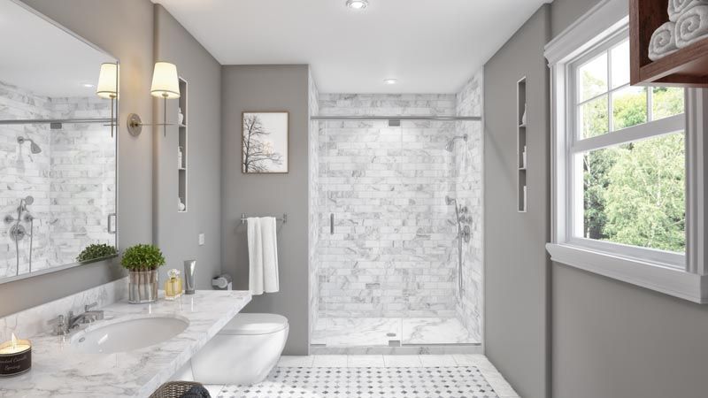 Modern bathroom with marble accents, gray walls, and a window.