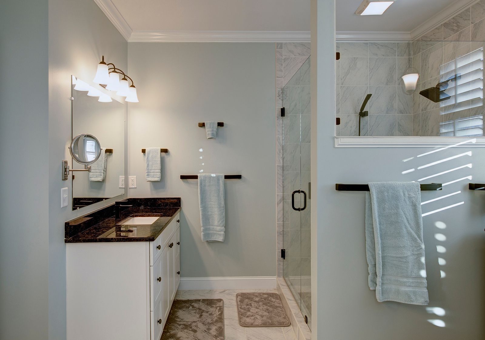 Bathroom with white vanity, glass shower, and light blue walls.