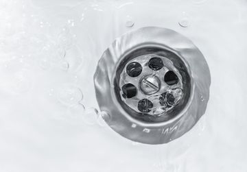 Water flowing into a shiny metal sink drain.