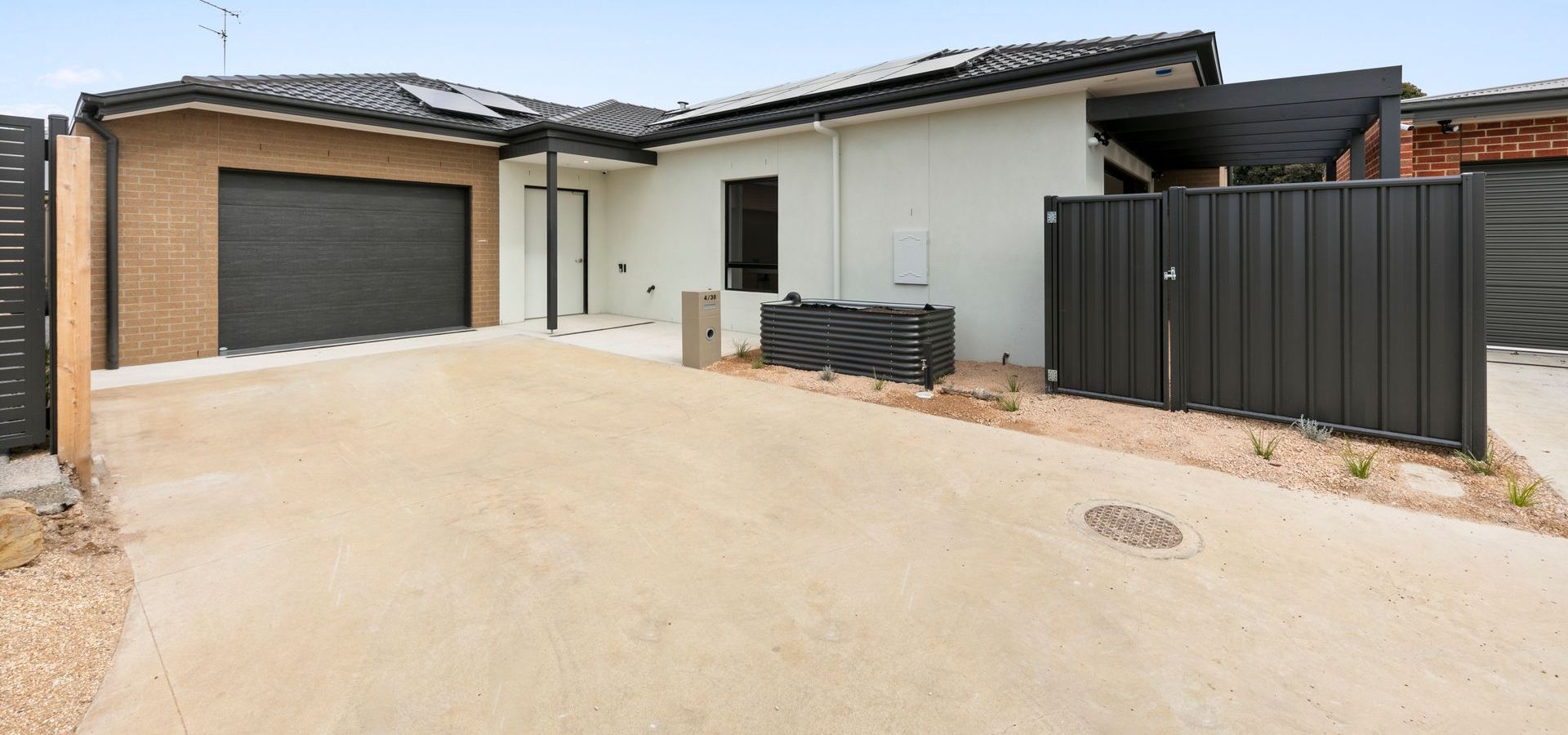 A white house with a black garage door and a black fence.