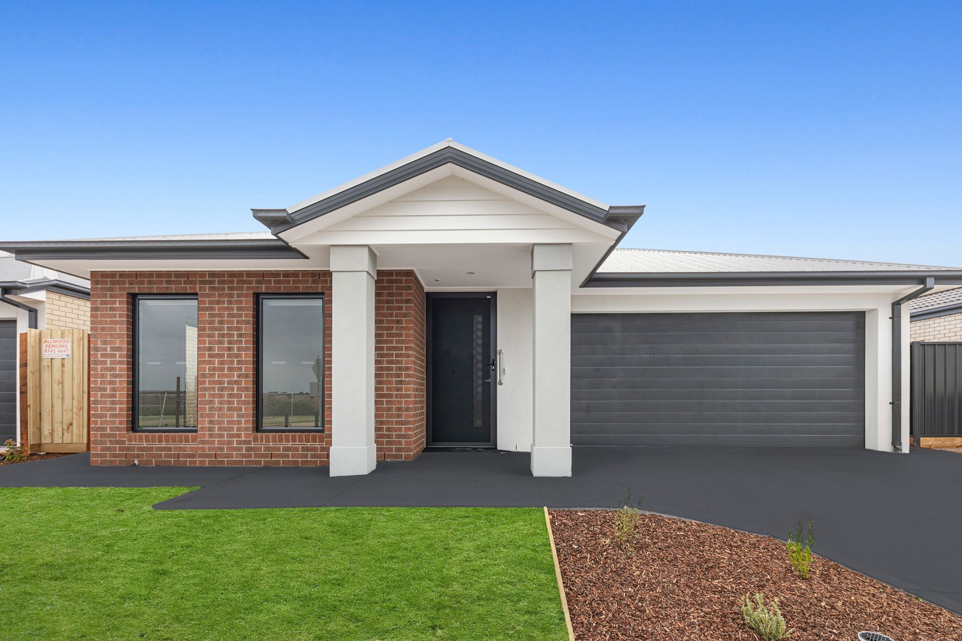 The front of a brick house with a black garage door.