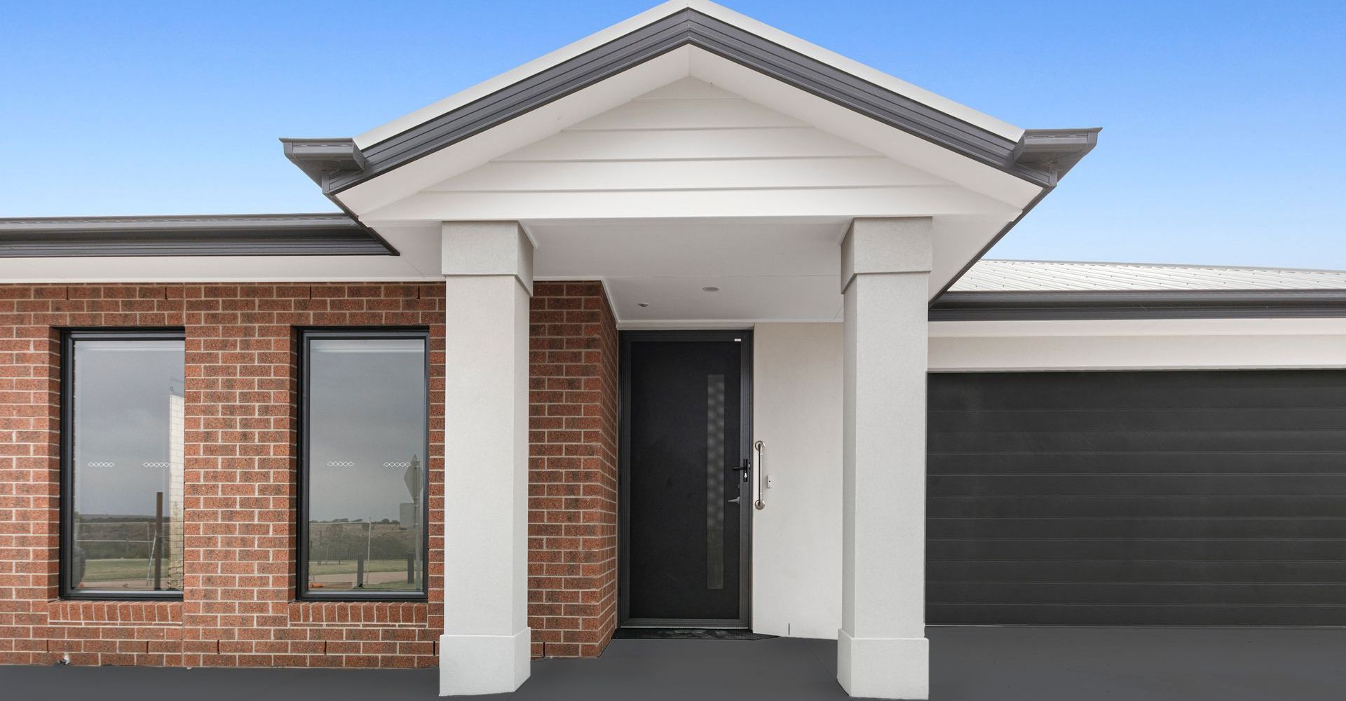 The front of a brick house with a porch and a garage.