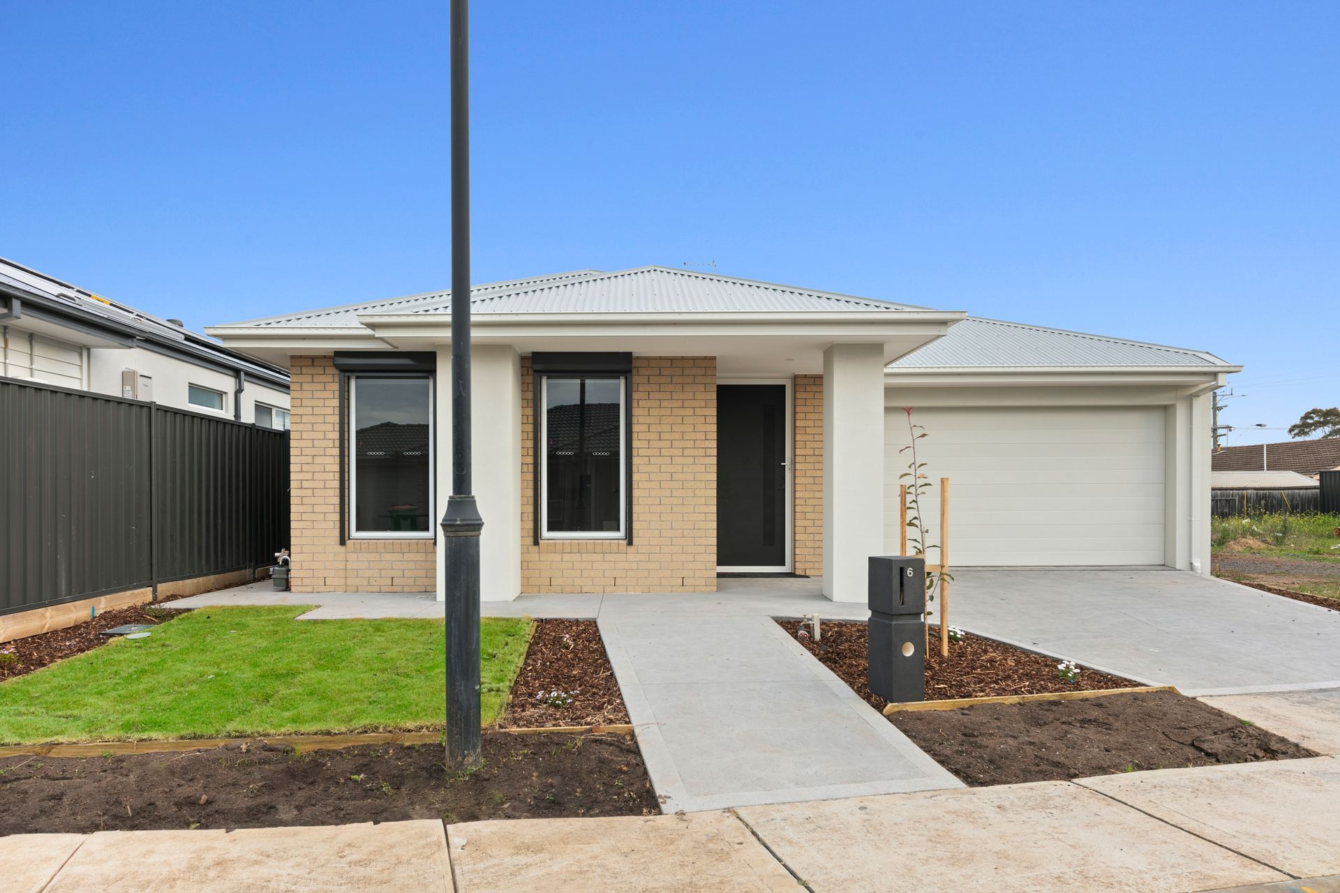 A brick house with a white roof and a black fence