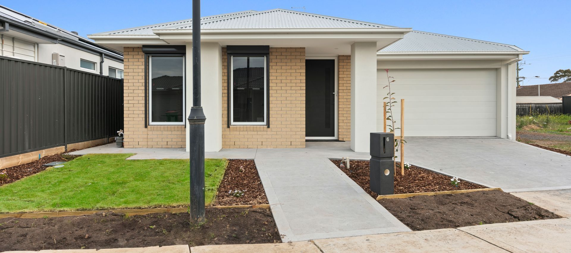 A brick house with a white garage door and a black fence