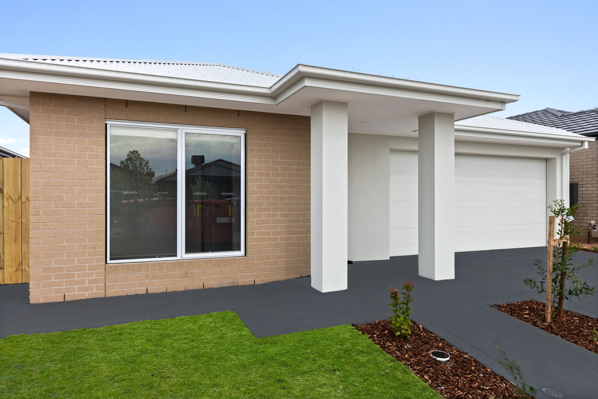 A small brick house with a white garage door and a large window.