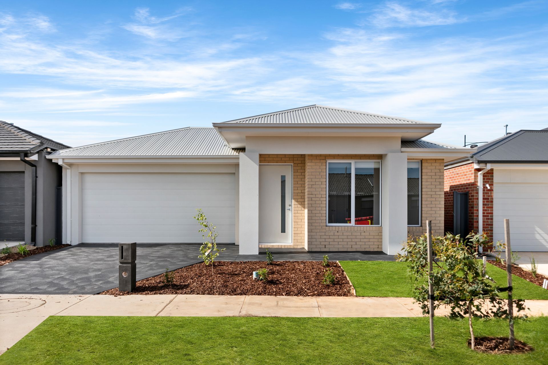 A house with a white garage door is sitting on top of a lush green lawn.