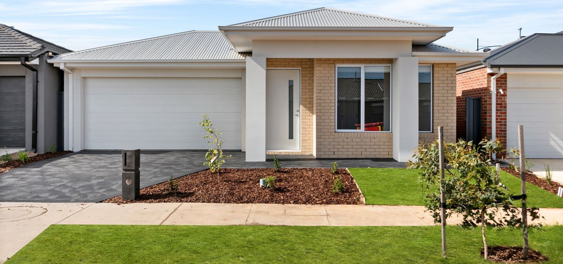 A brick house with a white garage door and a walkway in front of it.