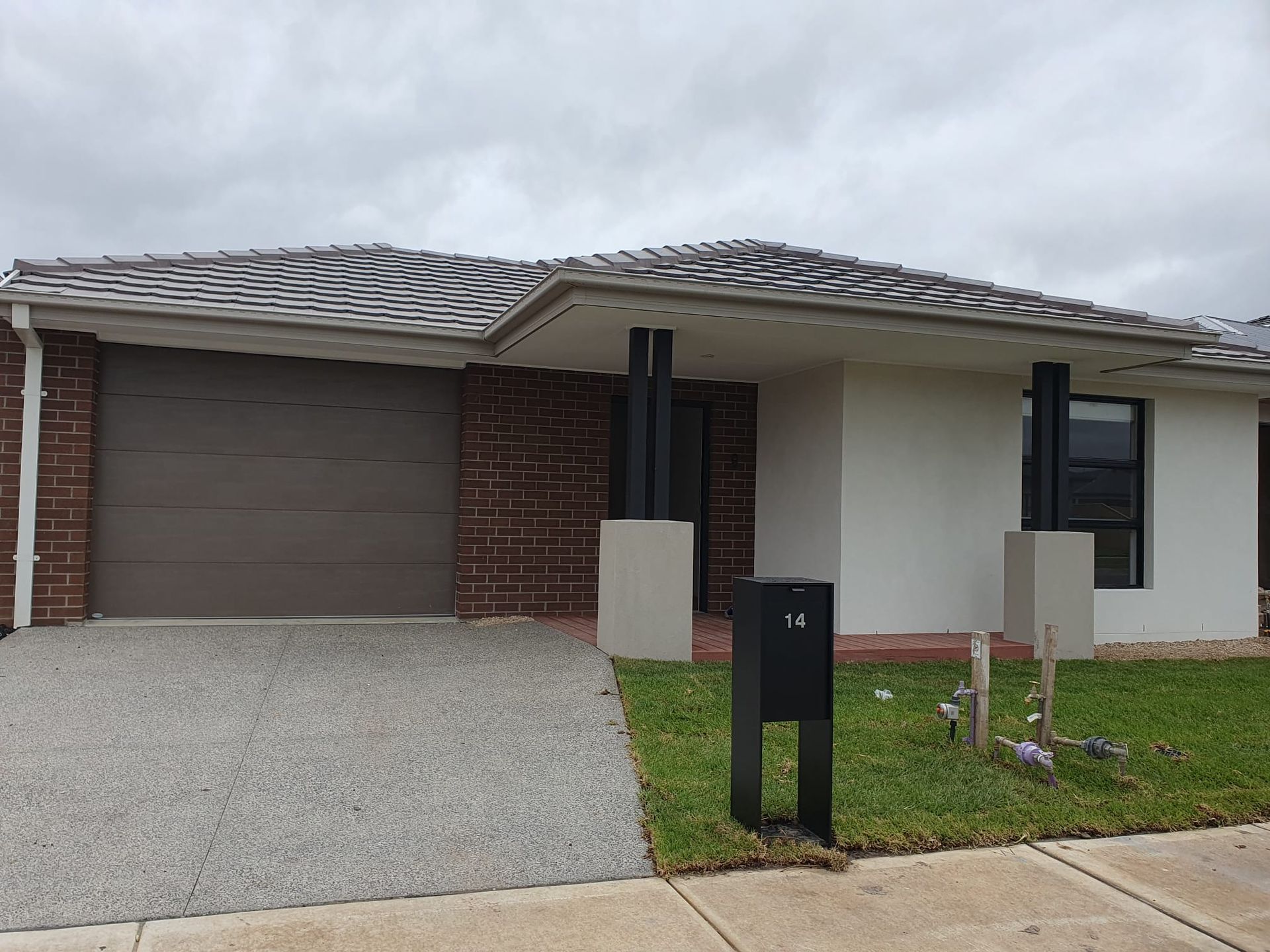 A white house with a brown garage door and a black mailbox