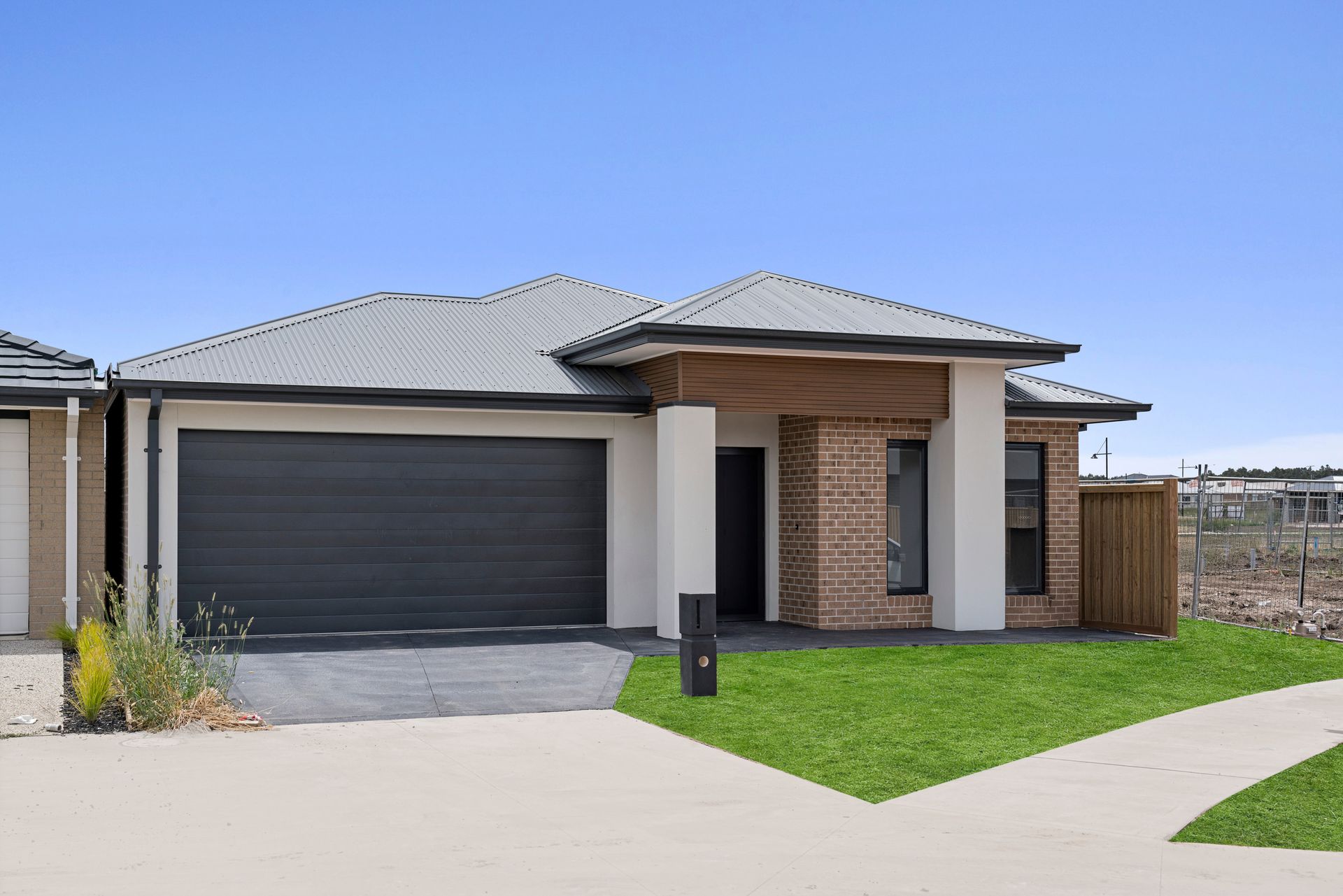 The front of a brick house with a black garage door.