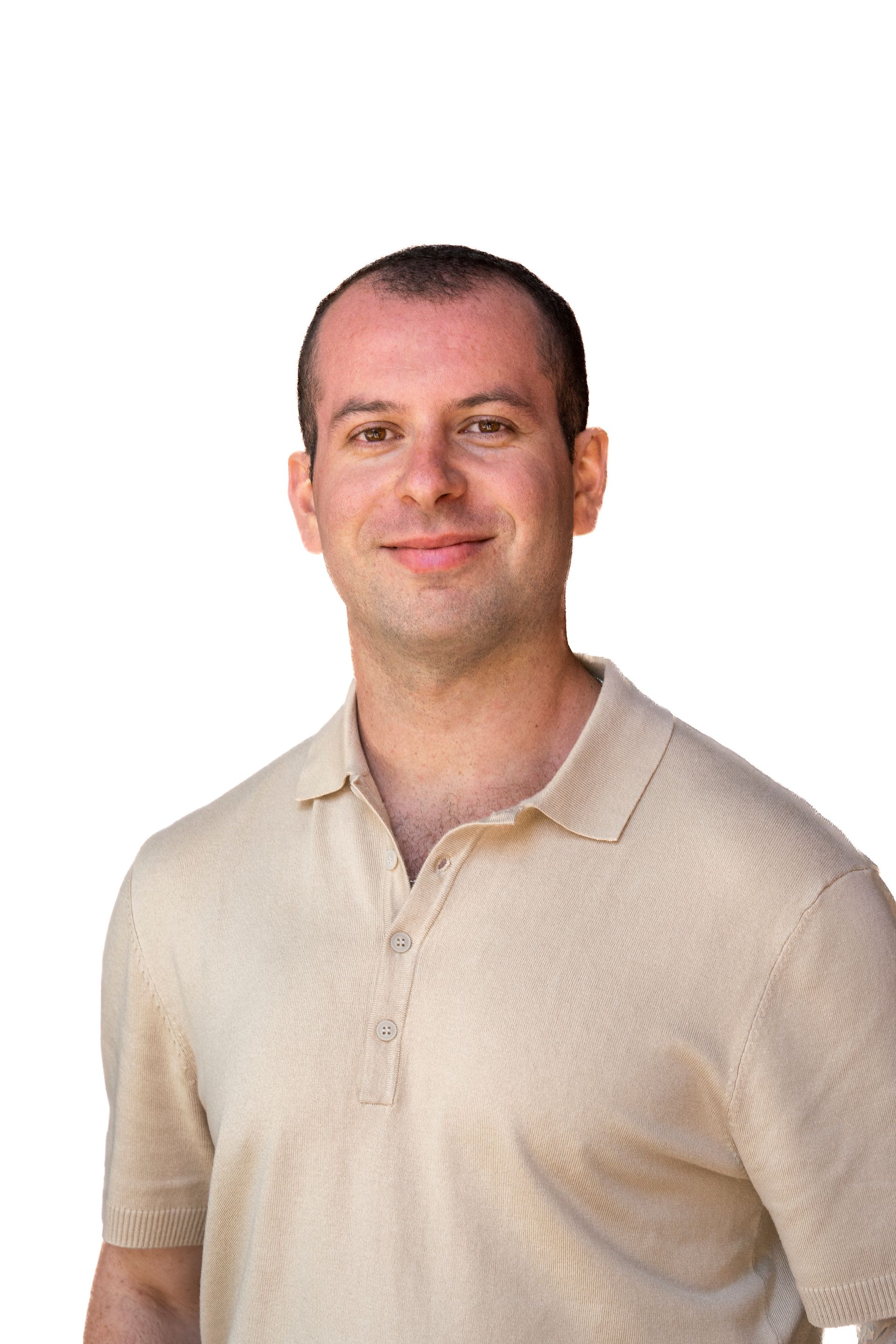 A man with a beard is wearing a white shirt and smiling.