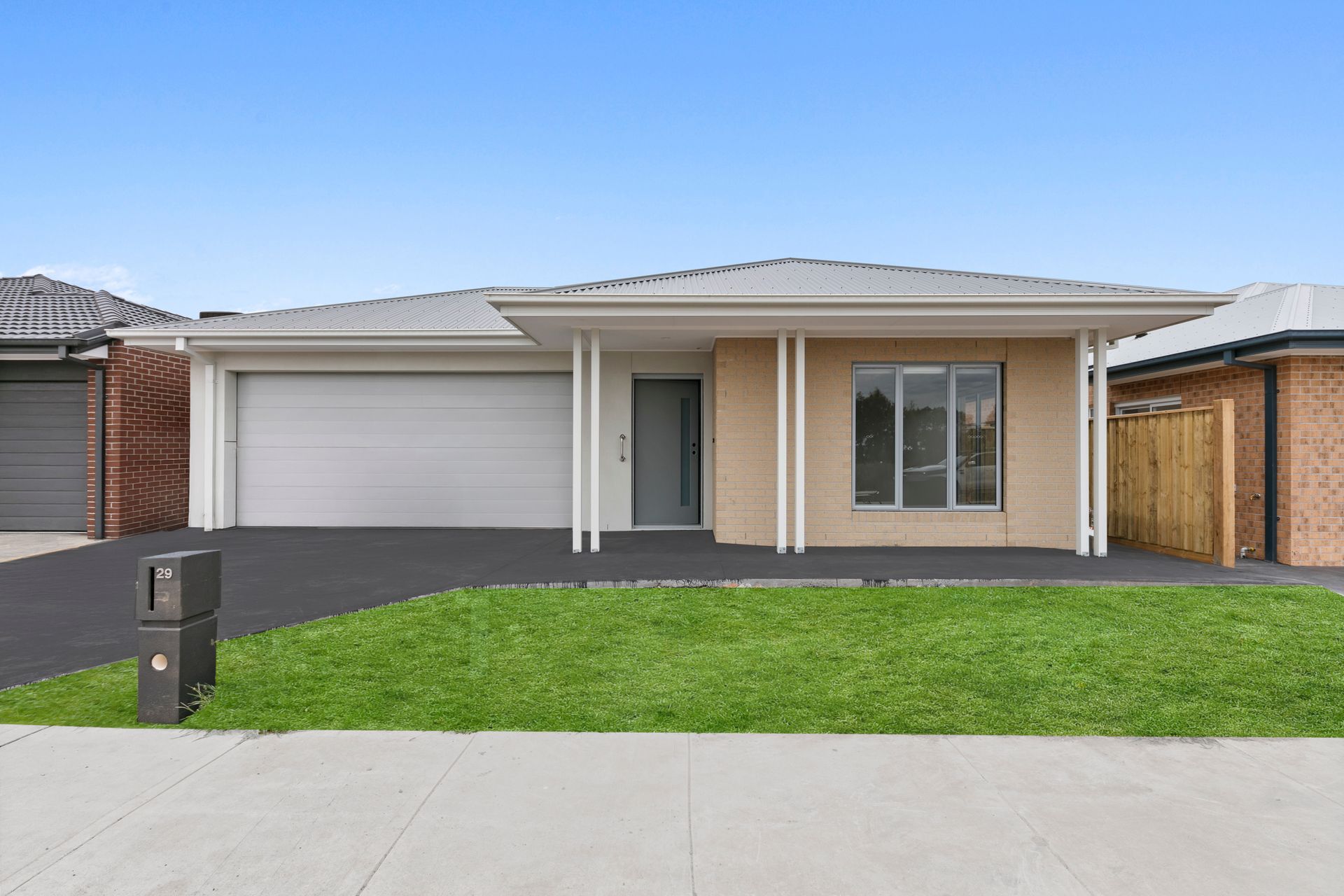 A car is parked in front of a house with a garage.