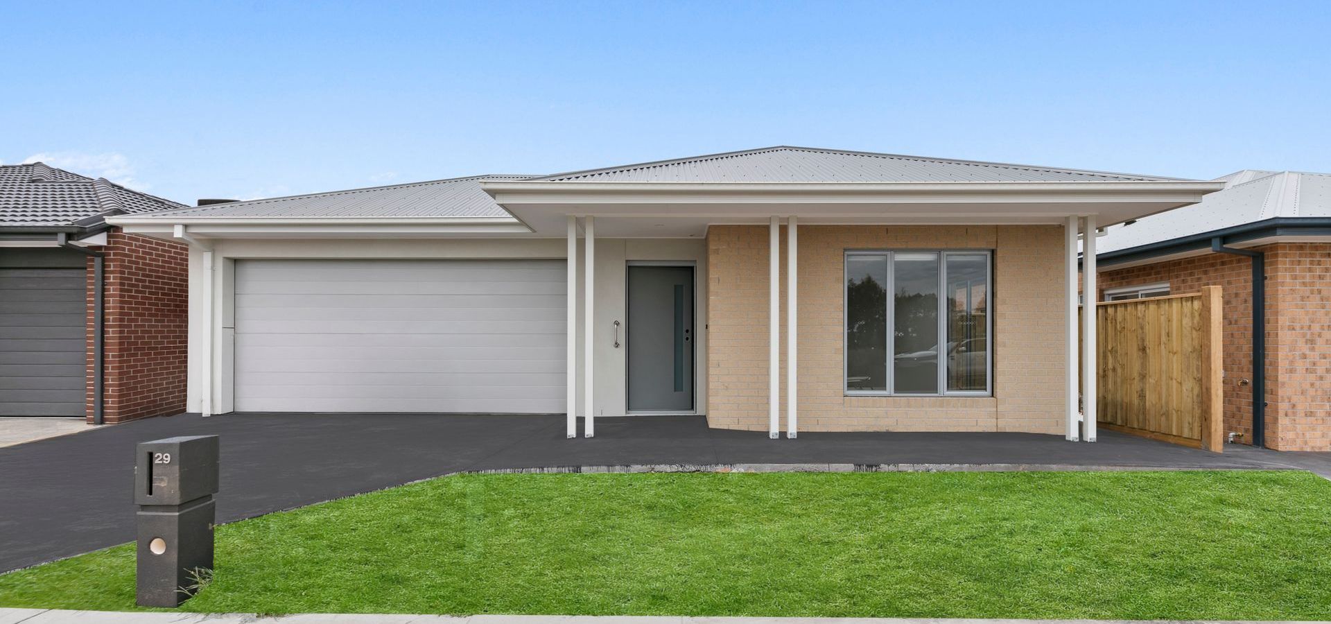 A car is parked in front of a house with a garage.