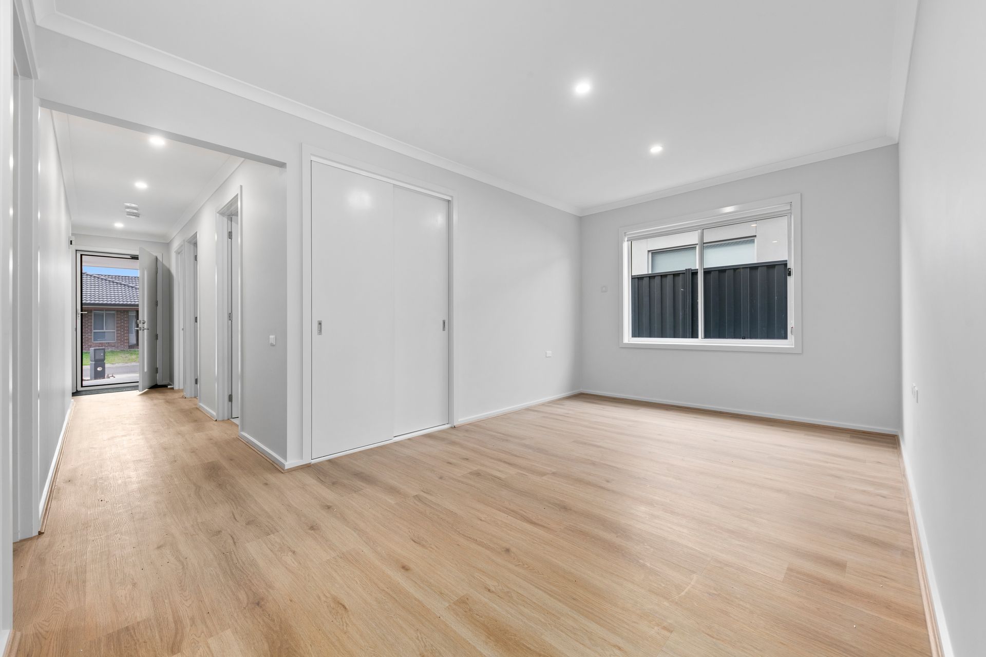 An empty living room with hardwood floors and white walls.