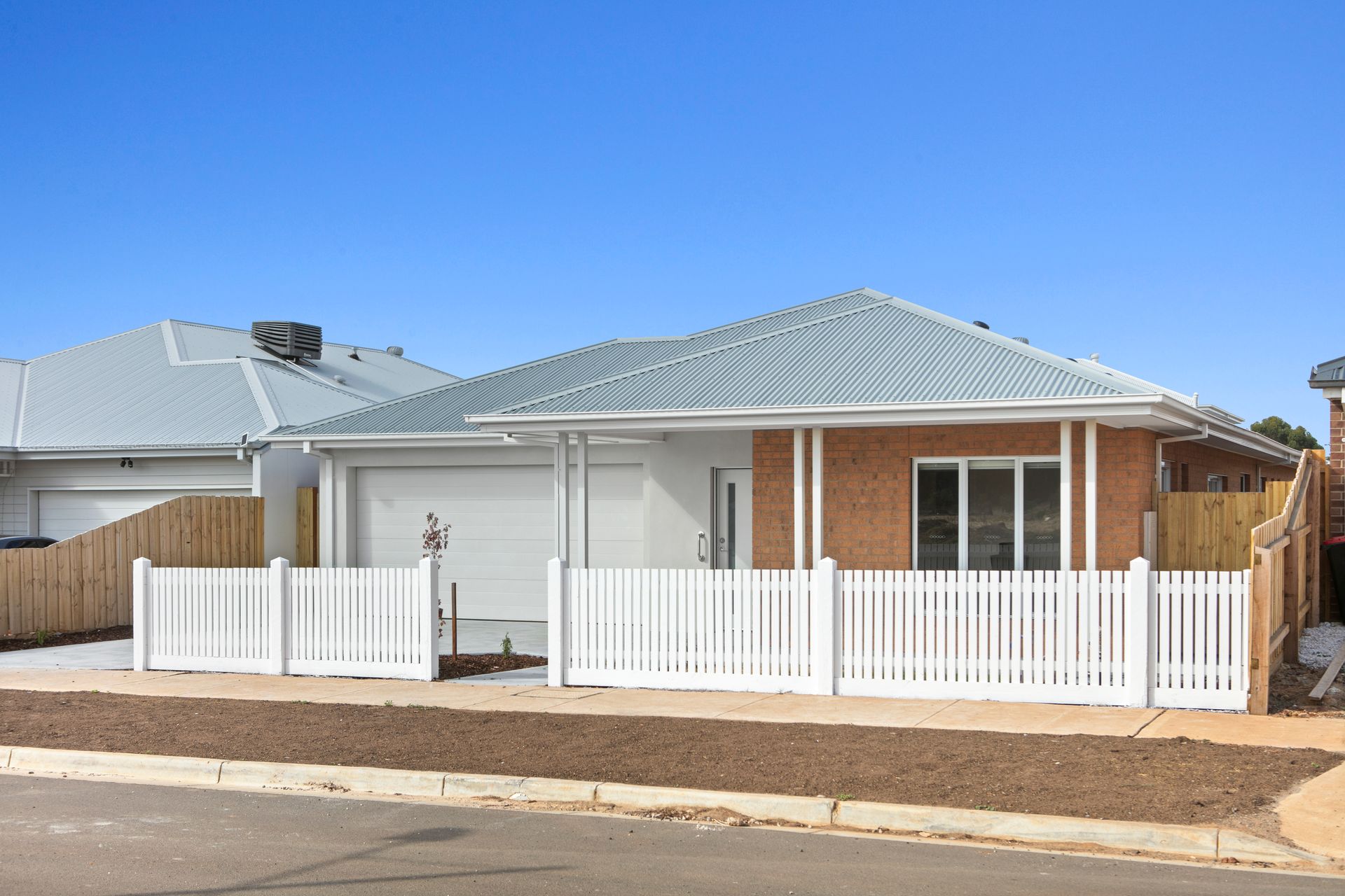 A house with a garage and a wooden fence in front of it.