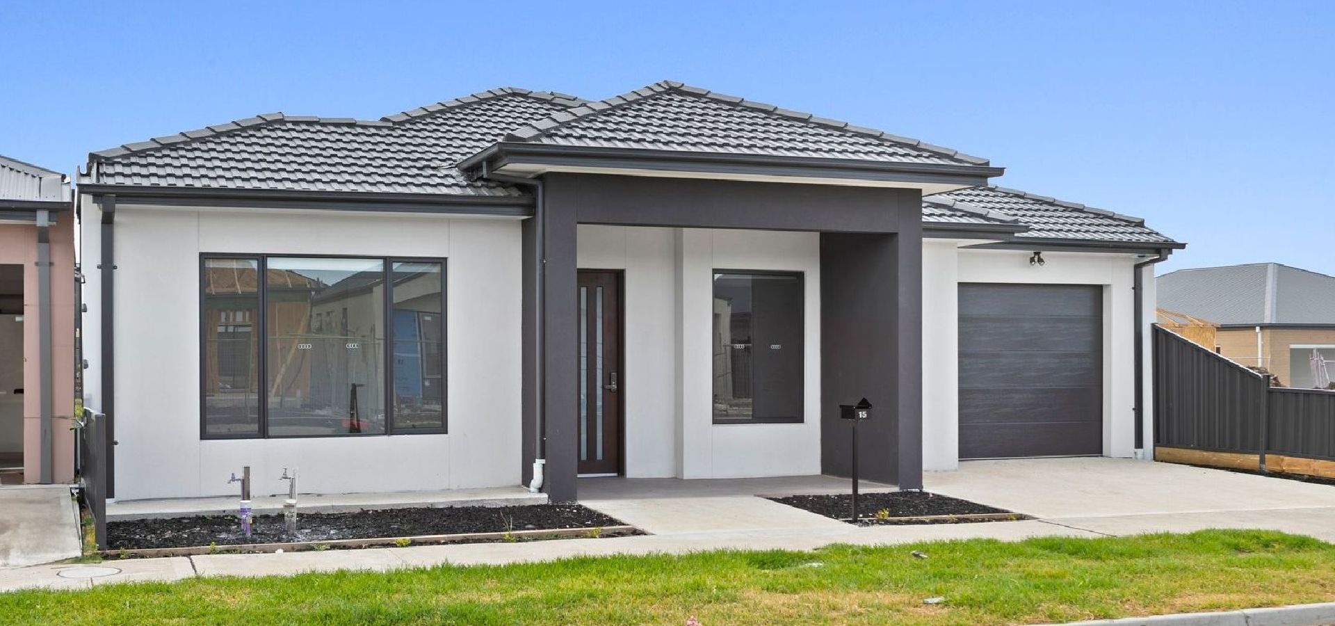 A house with a garage and a fence in front of it.