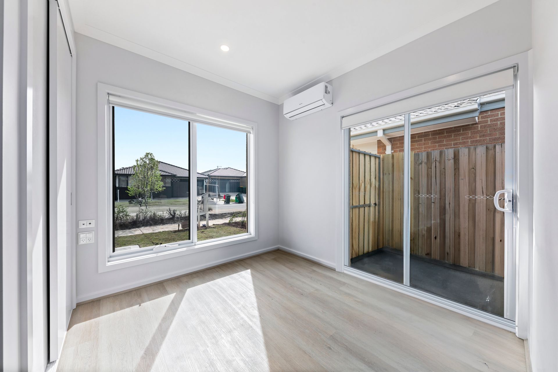 An empty room with a lot of windows and sliding glass doors.