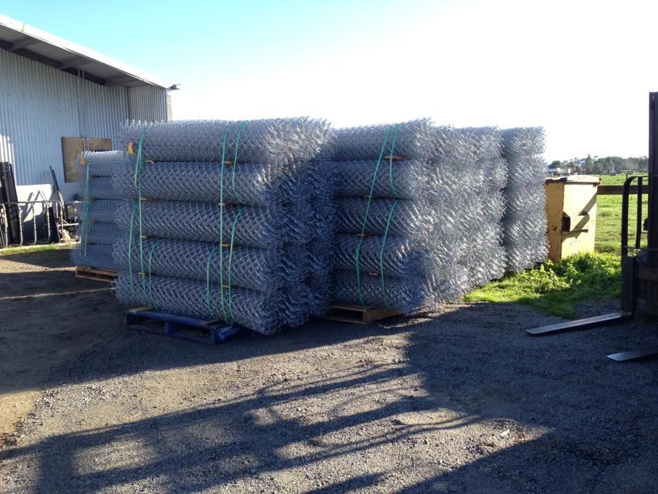 A stack of chain link fence is sitting on a pallet in a parking lot.