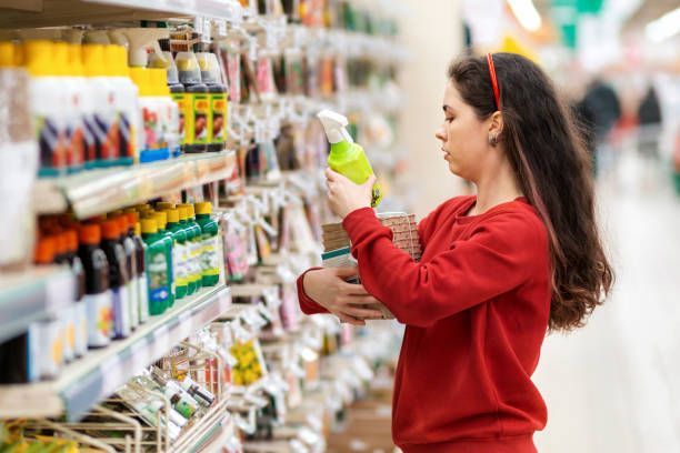 A woman in a red sweater is holding agricultural supplies, such as seeds and a fertiliser. 