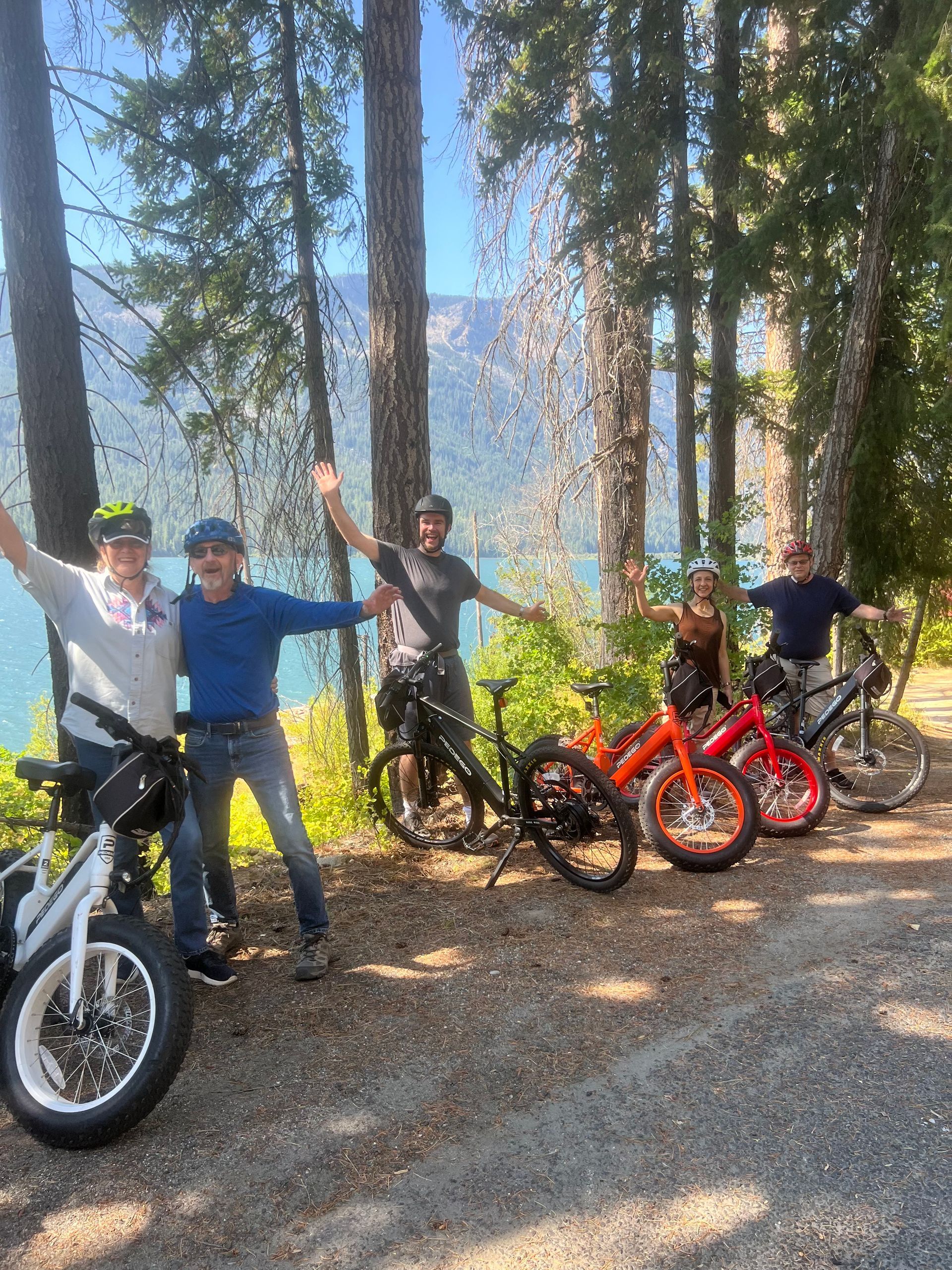 A group of people are posing for a picture with their bikes in the woods.