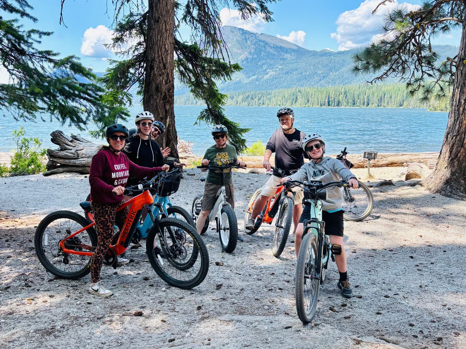 A group of people are posing for a picture with their bikes in the woods.