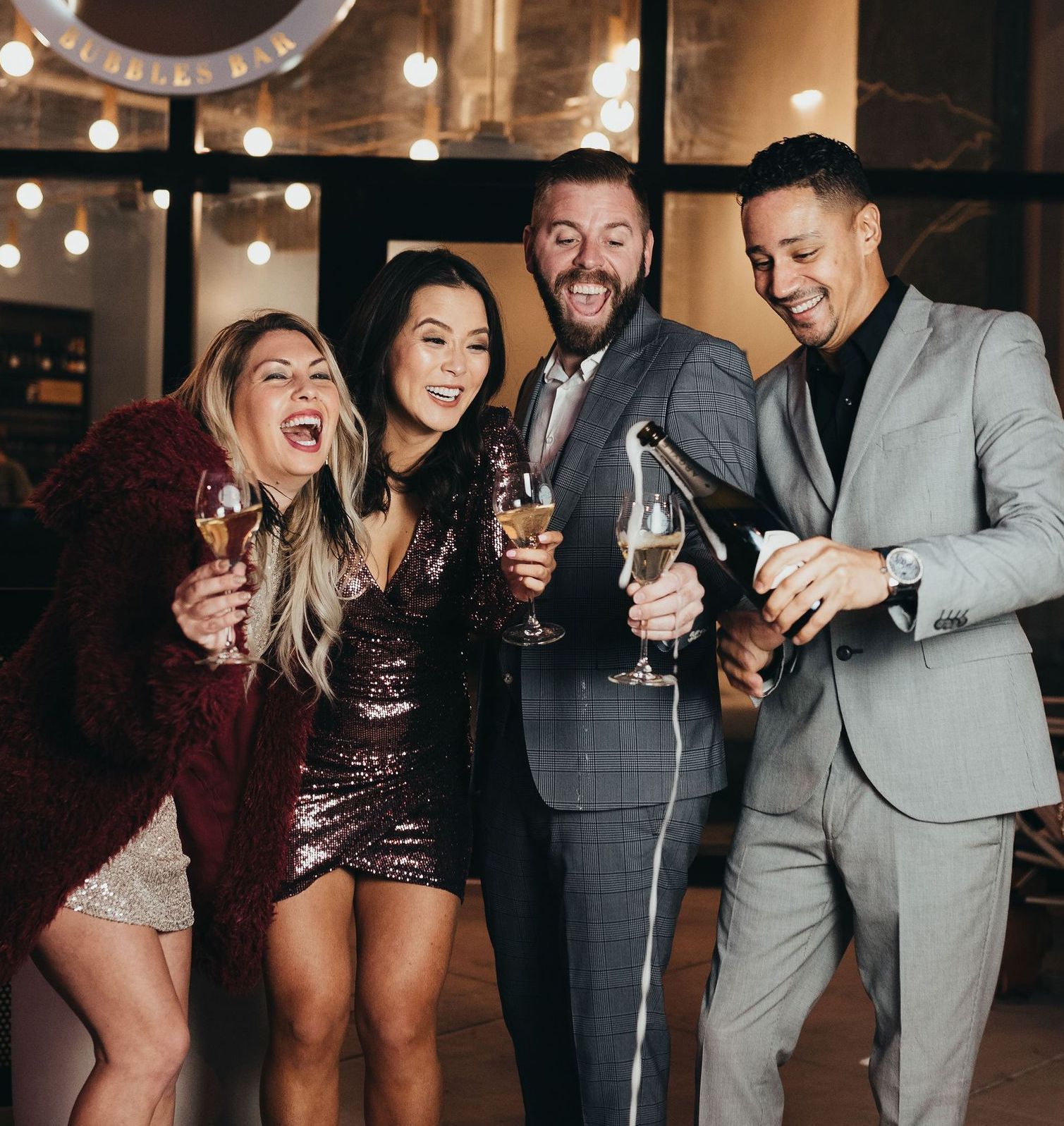 A group of friends popping bottles of champagne outside of Fizz Champagne & Bubbles Bar in Sacramento, CA.
