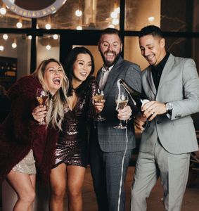 People popping bottles of champagne outside of Fizz Champagne & Bubbles Bar.