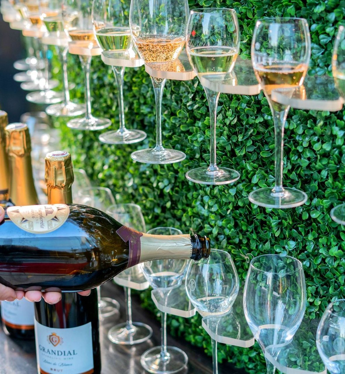 champagne being poured into glasses on a champagne wall at Fizz Champagne & Bubbles Bar.