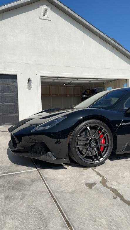 A black sports car is parked in front of a garage.