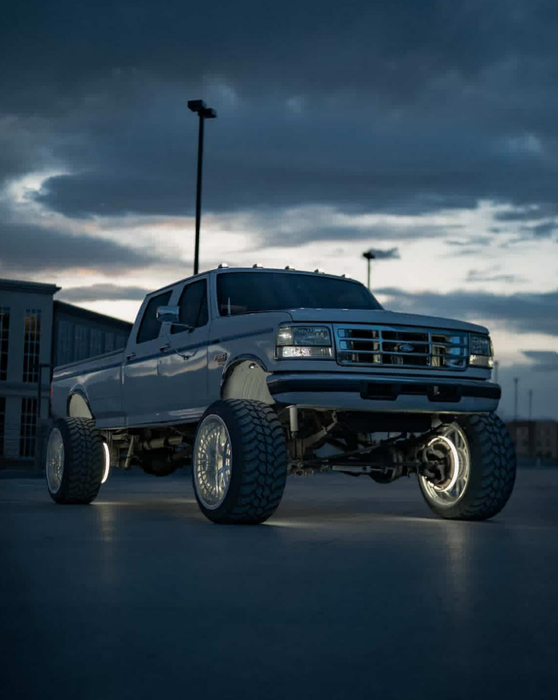 A ford truck is parked in a parking lot at night.