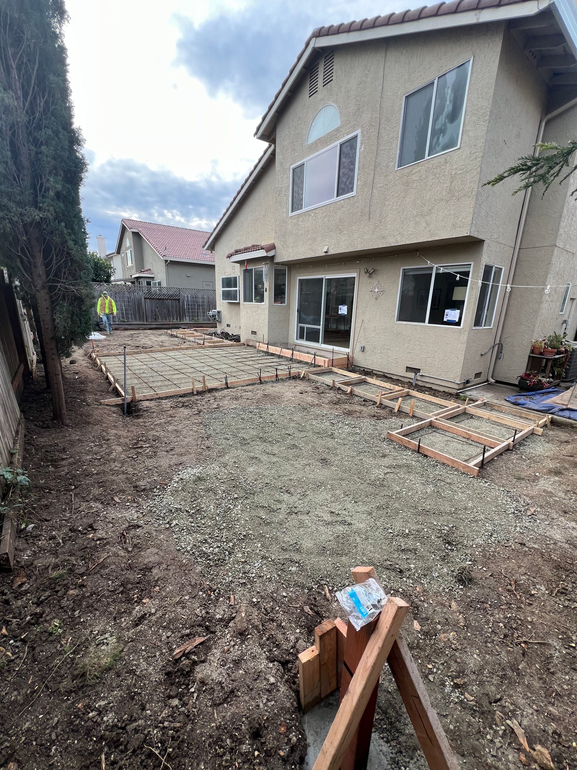 Backyard under construction with gravel and brick edging. Beige house in background.