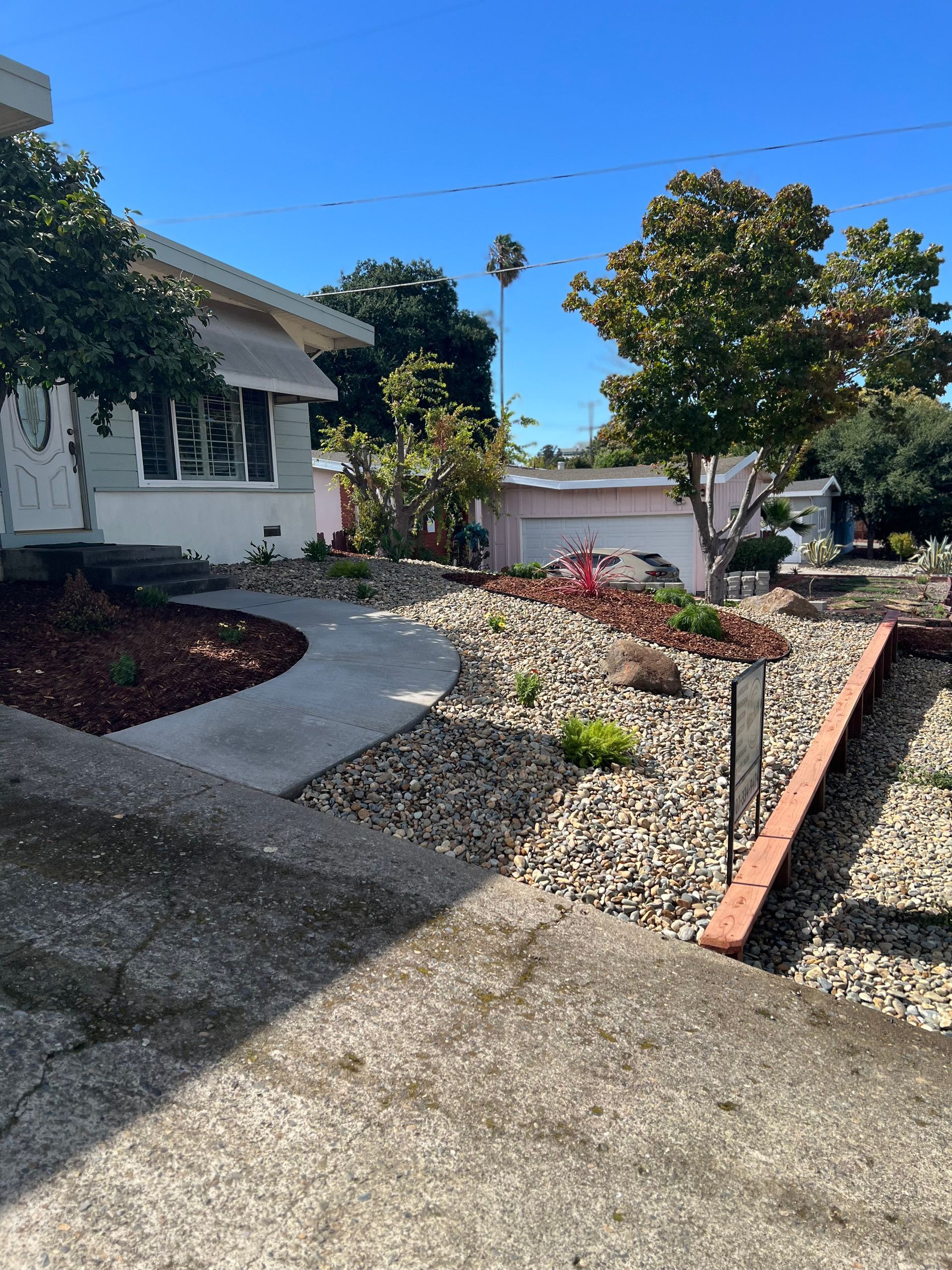 Curb appeal: a light-colored house with a rock garden pathway and a low retaining wall under a blue sky.