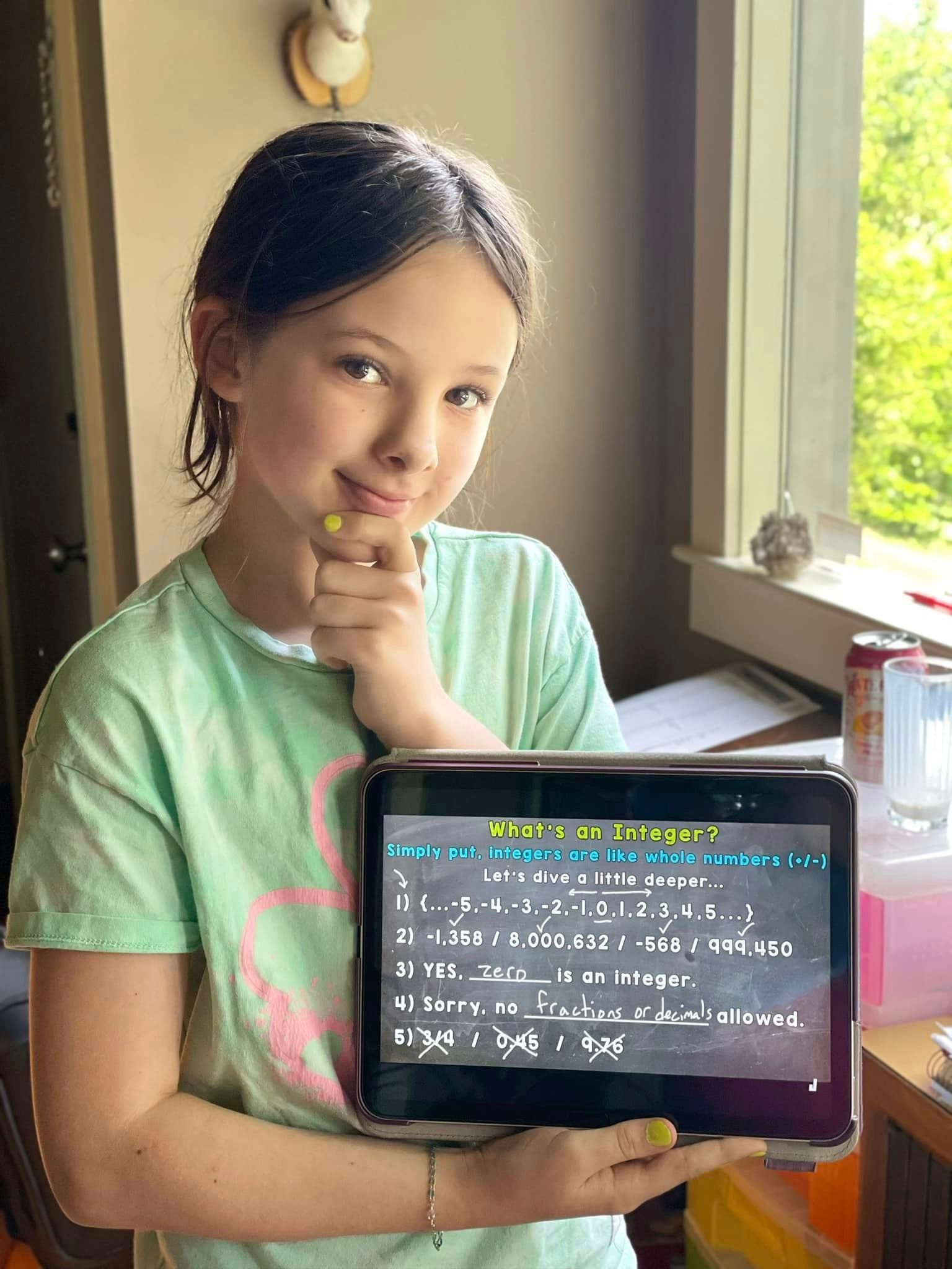 A young girl is holding a tablet computer in her hands.