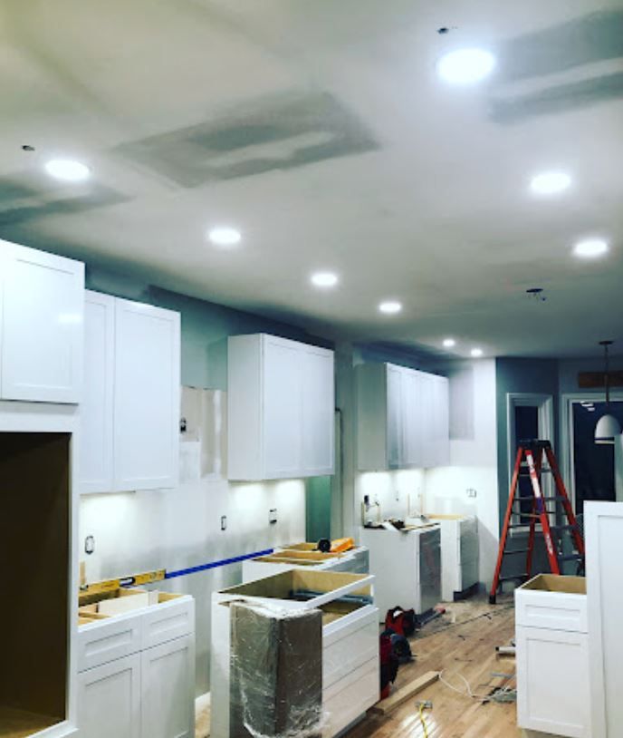 A kitchen under construction with white cabinets and a red ladder