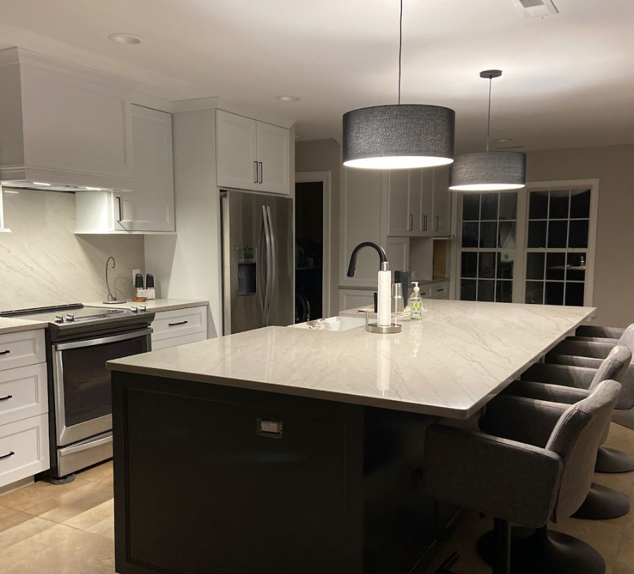 A kitchen with a large island , stove , refrigerator , sink and chairs.