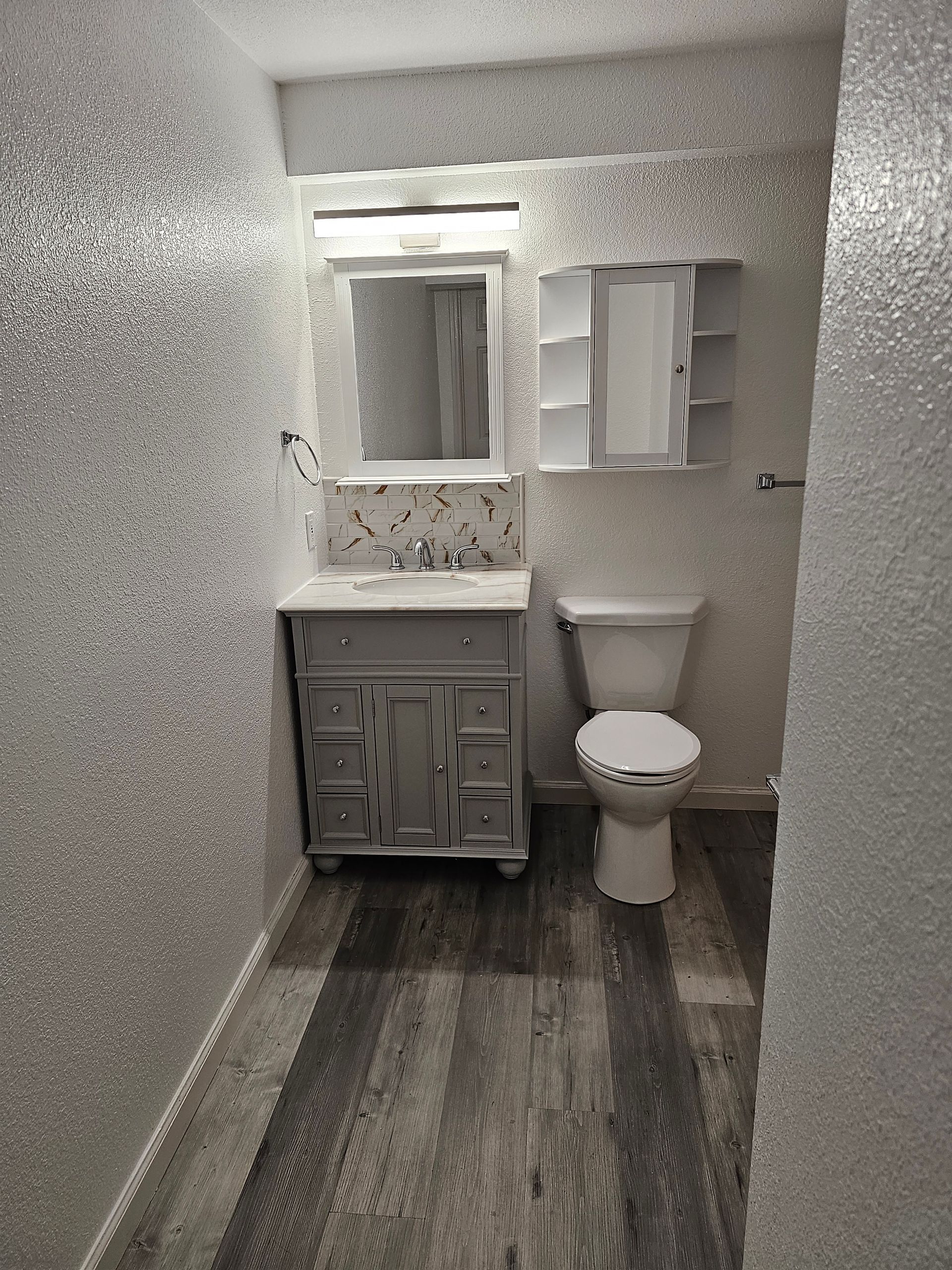 A bathroom with a sink , toilet and mirror.