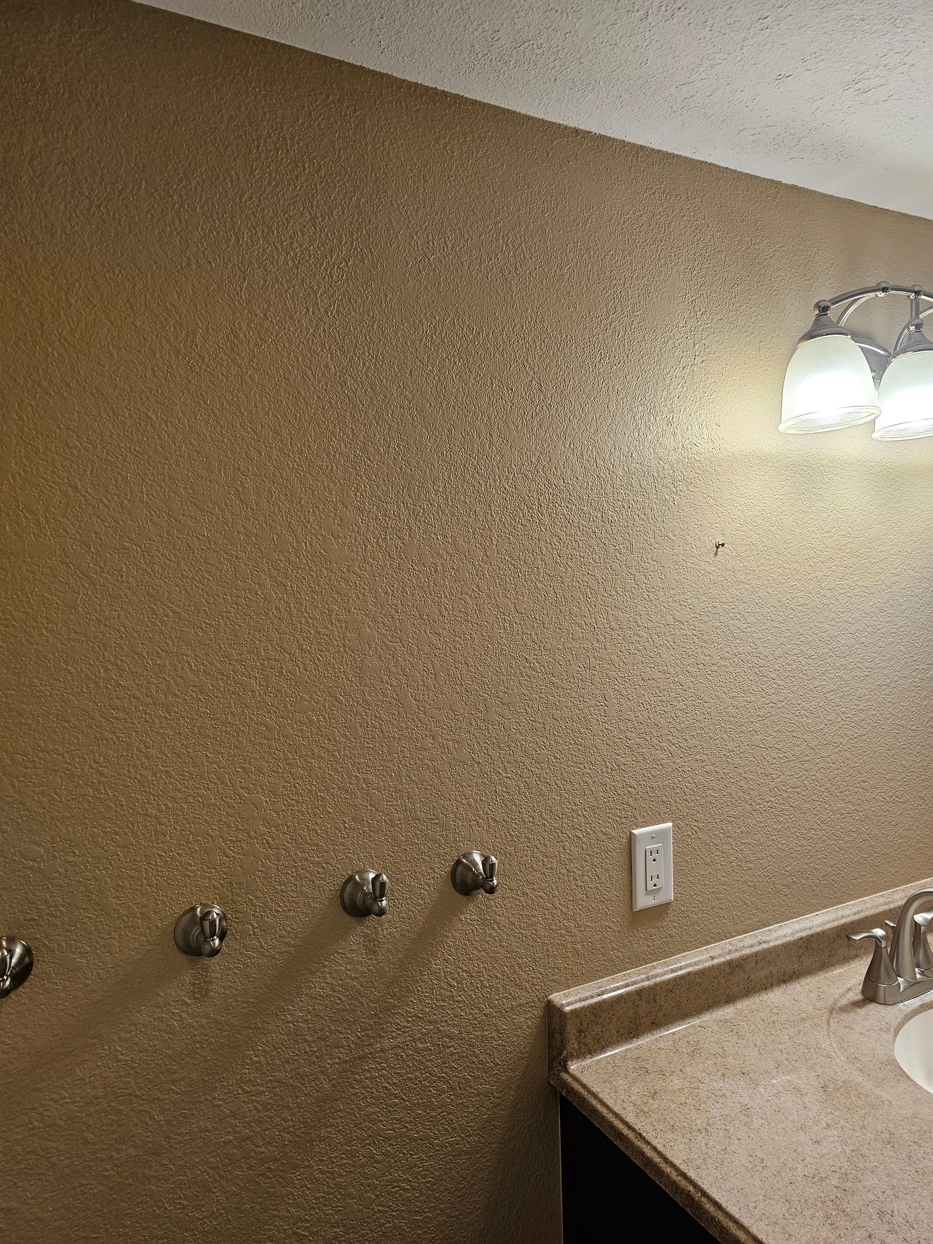 A bathroom with a sink and a light on the wall.