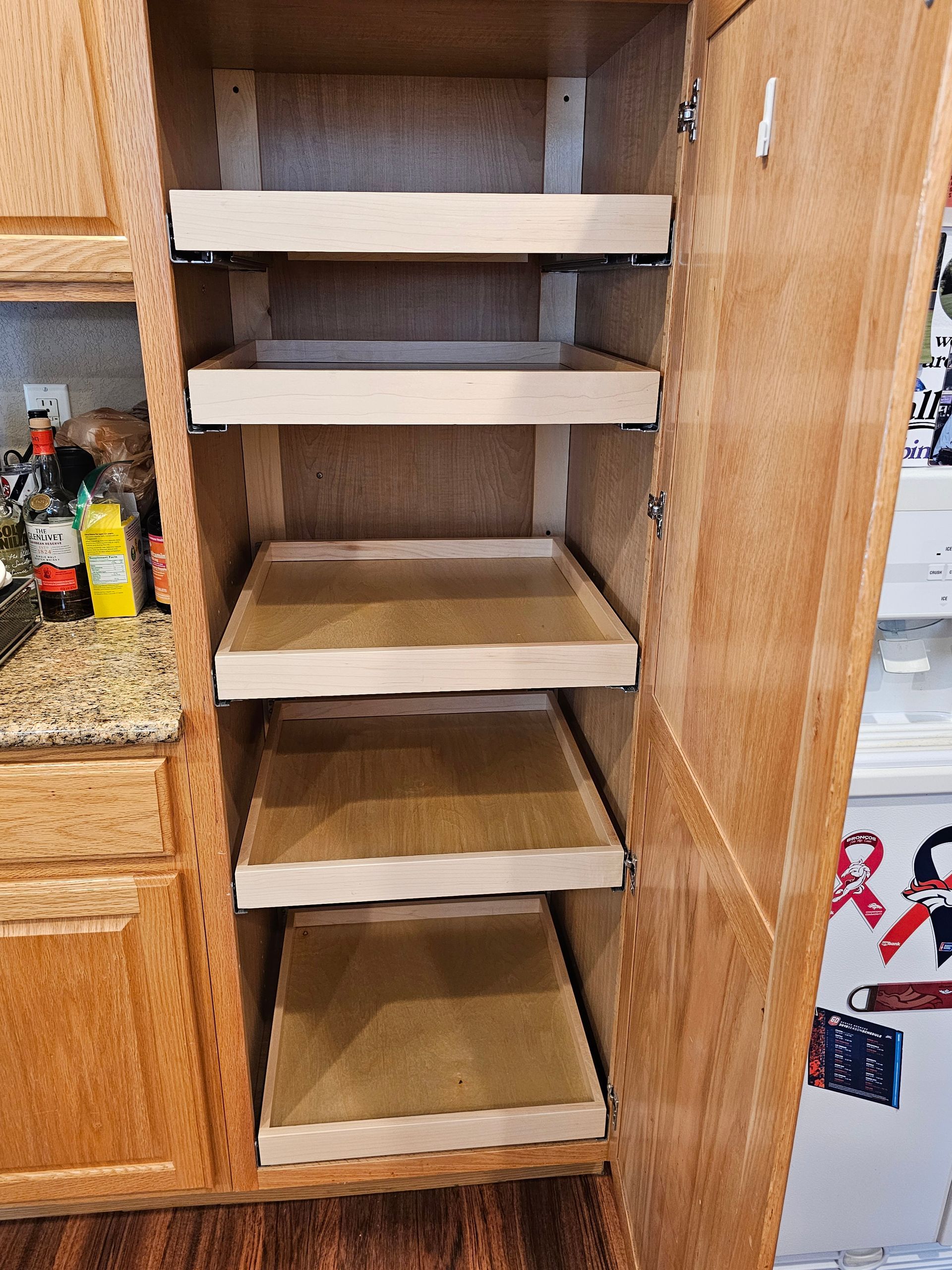 A kitchen cabinet with a bunch of shelves in it.