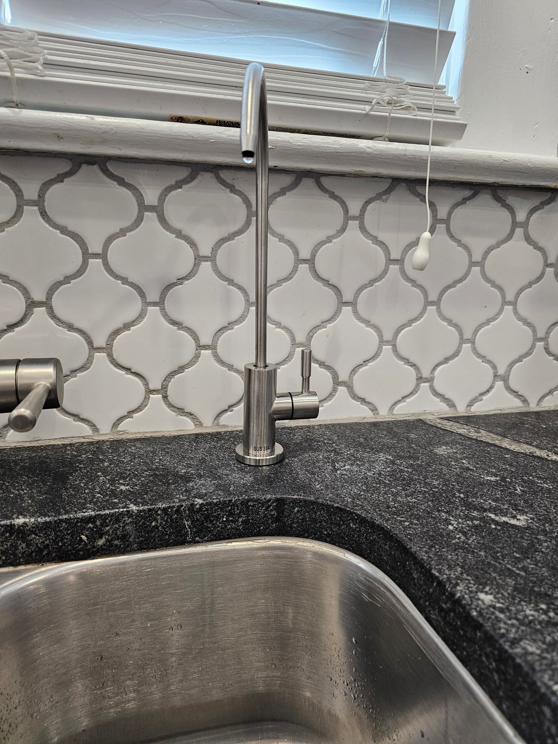A kitchen sink with a faucet and a keyboard on the counter.