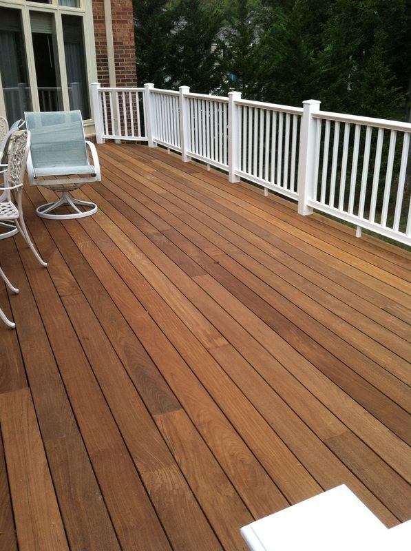A wooden deck with chairs and a white railing