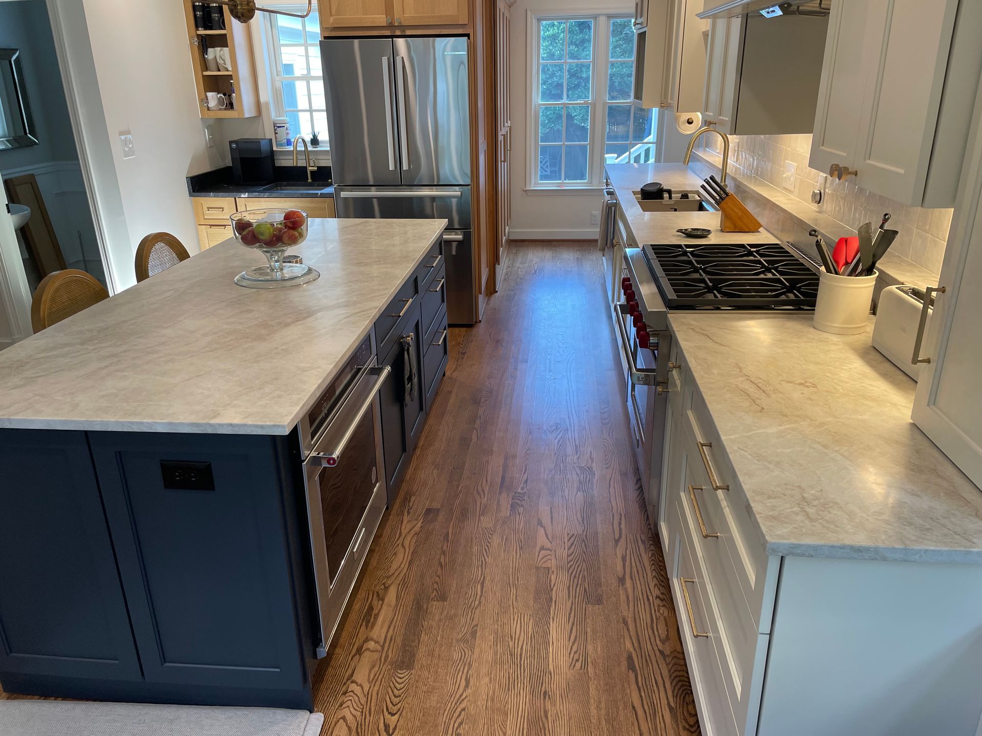 Kitchen with blue island, stainless steel appliances, and wood flooring.