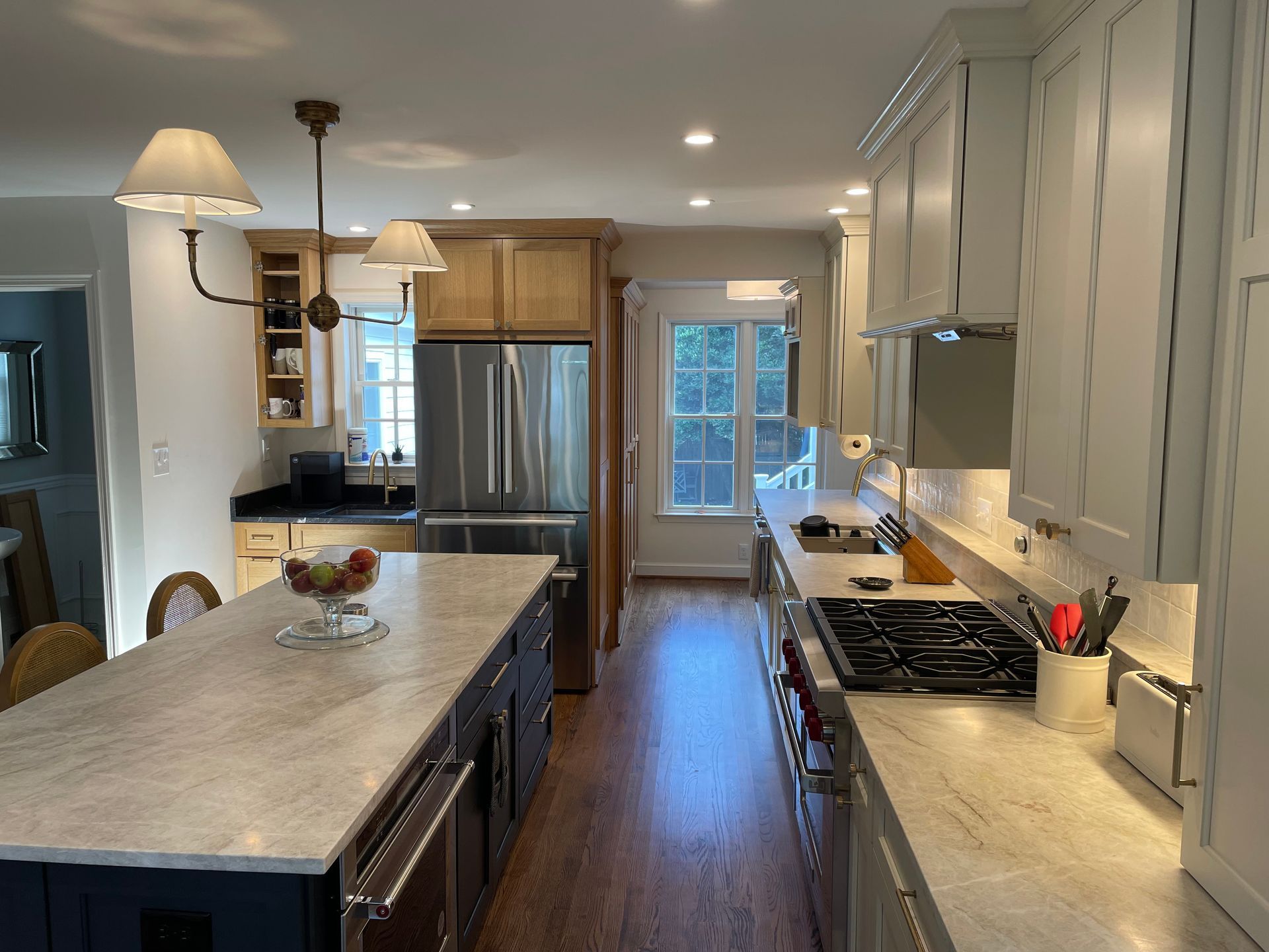 A kitchen with white and wood cabinets, a long island, and stainless steel appliances.
