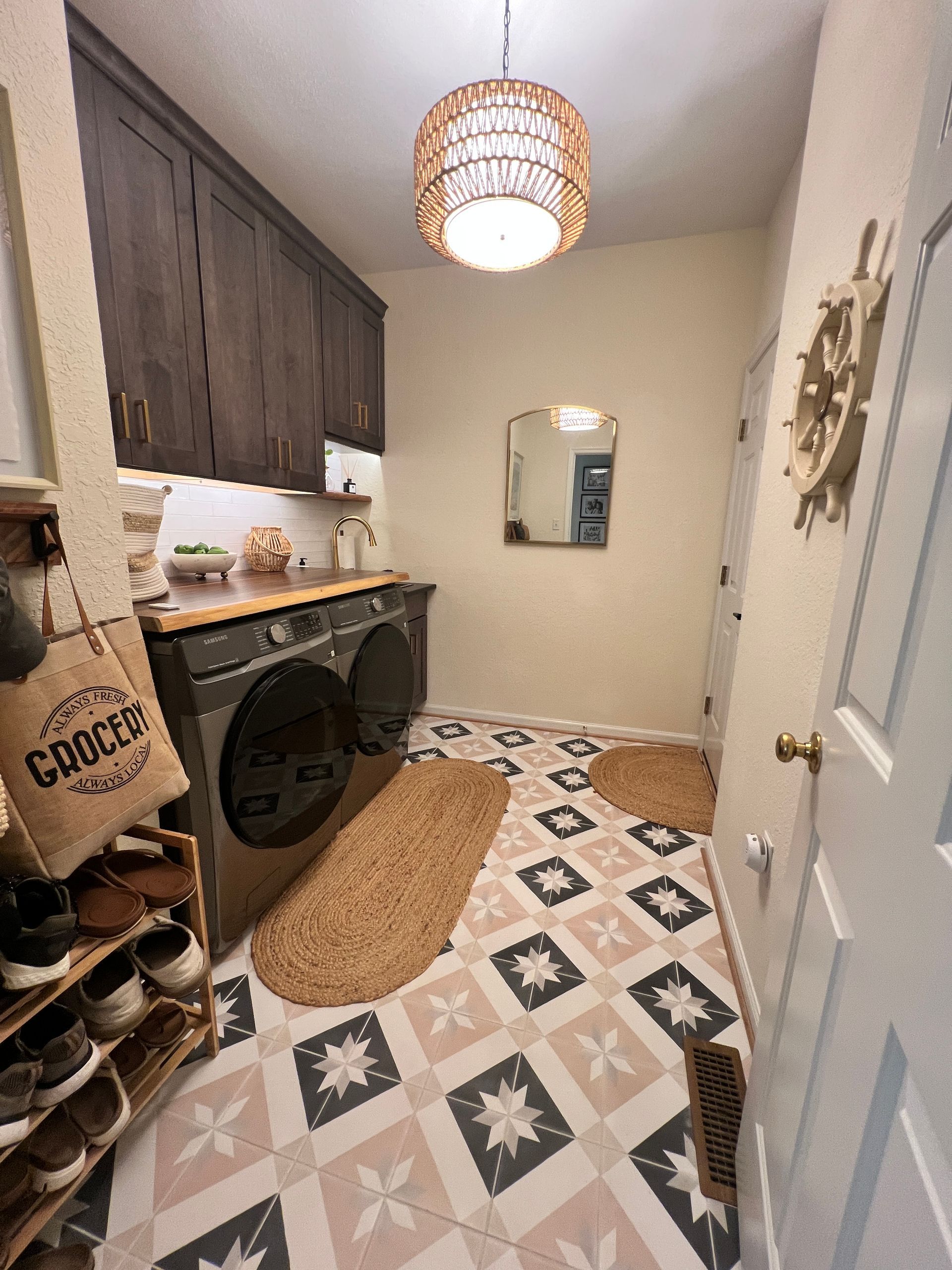 Laundry room with washer, dryer, cabinets, patterned floor, and woven light fixture.