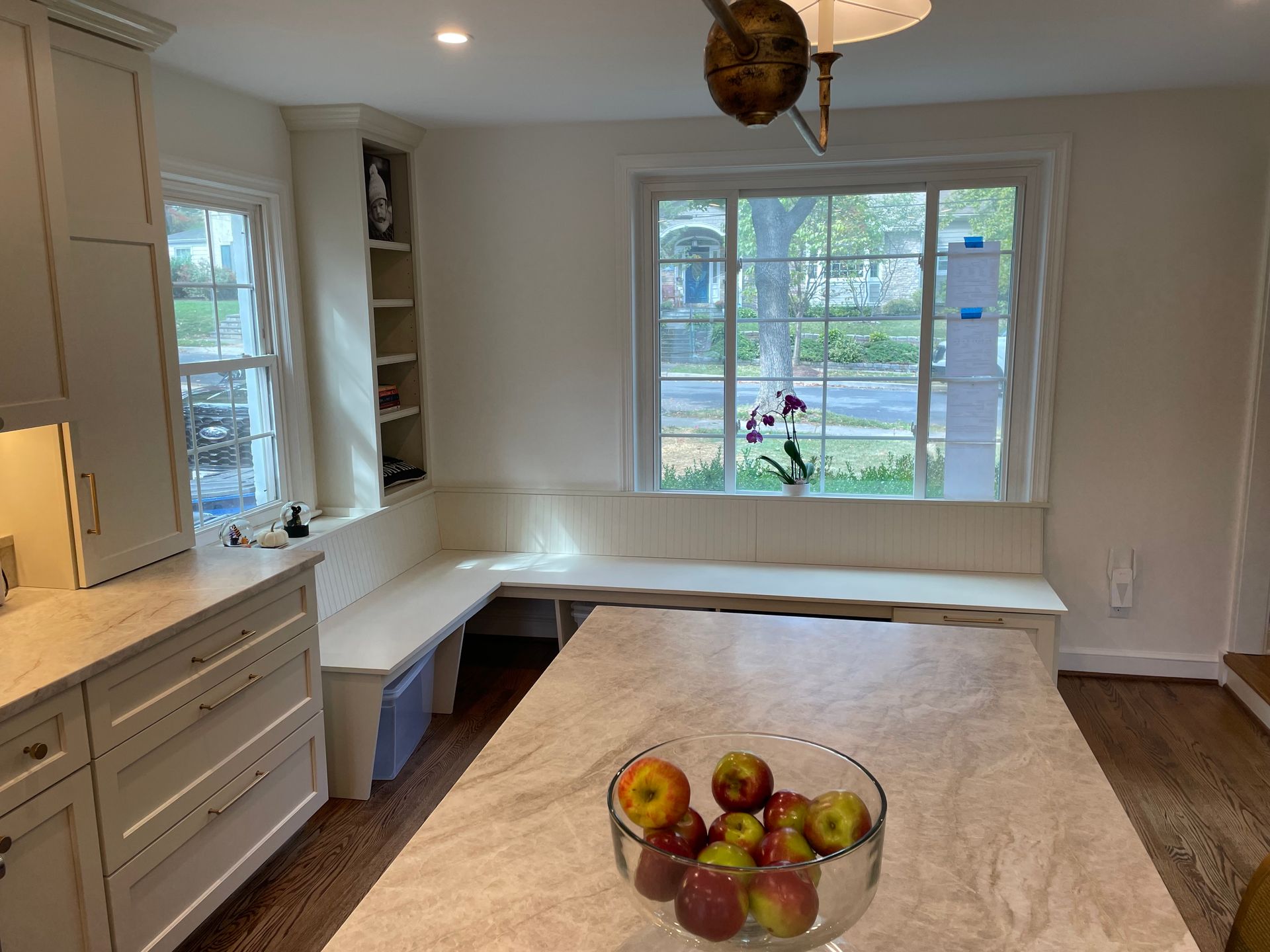 Kitchen with white cabinets, built-in bench seating, and an island with a fruit bowl.