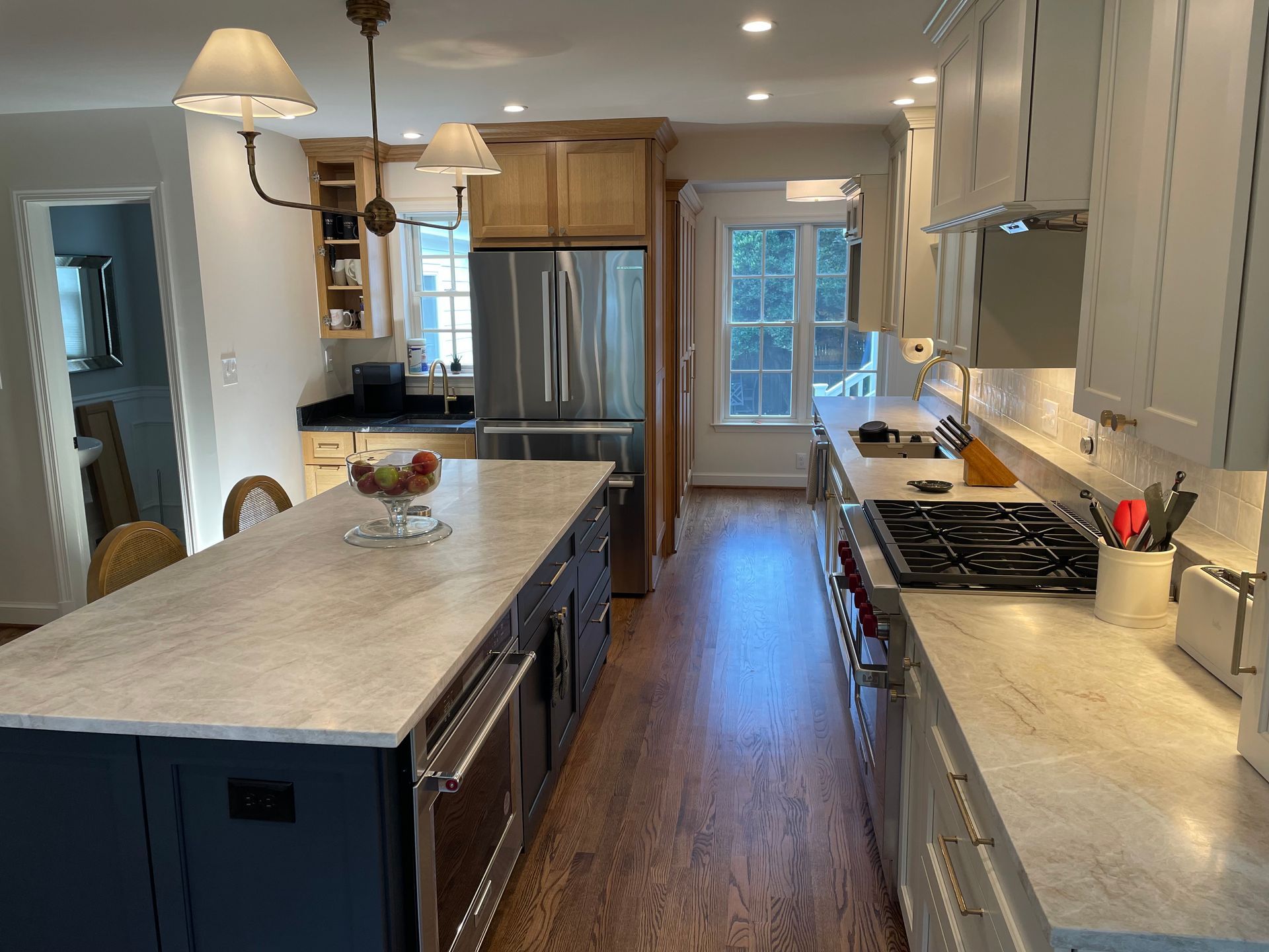 Modern kitchen with large island, stainless steel appliances, and white and blue cabinets.