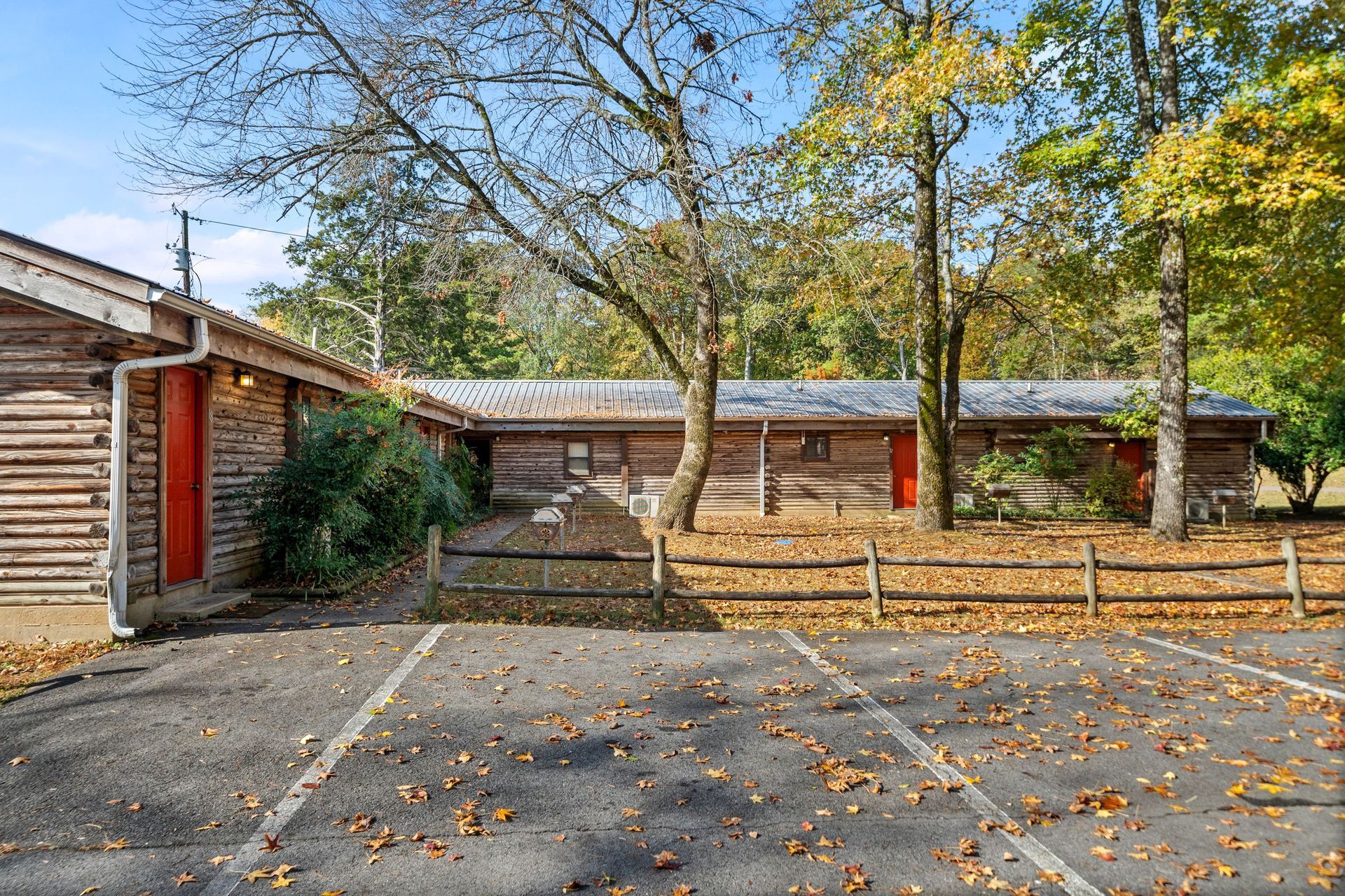 Log cabin style building with parking lot and trees; autumn leaves.