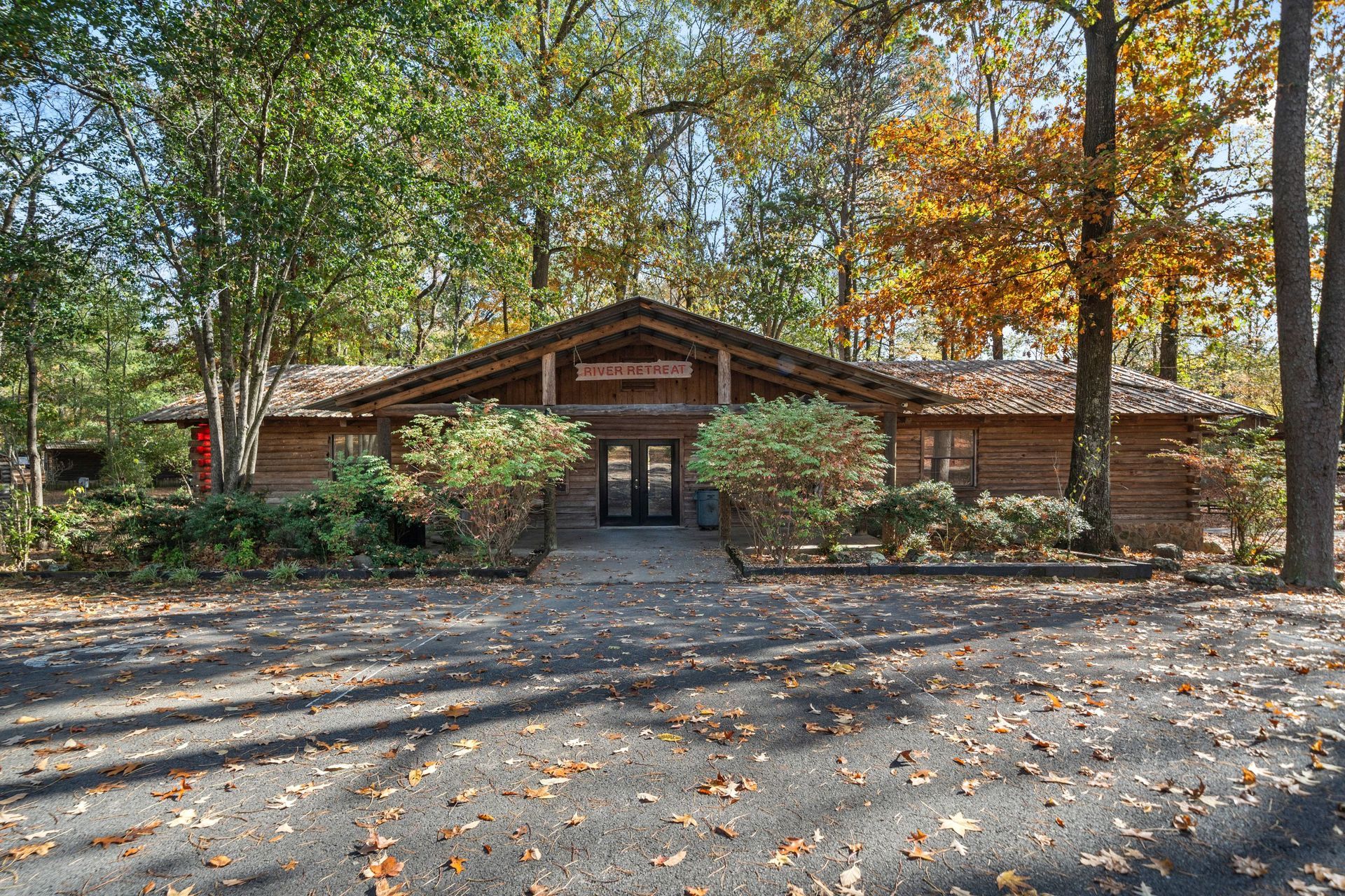 Rustic lodge building with dark double doors, surrounded by trees.