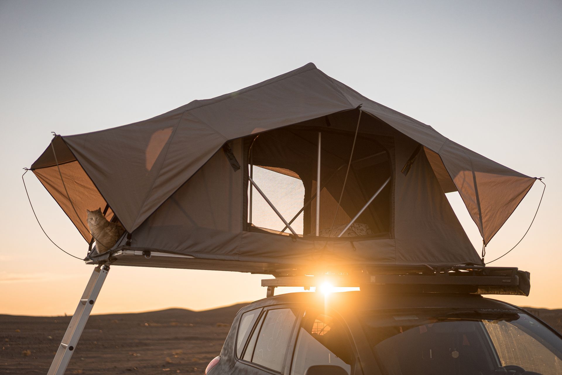 A rooftop tent is sitting on top of a car in the desert.