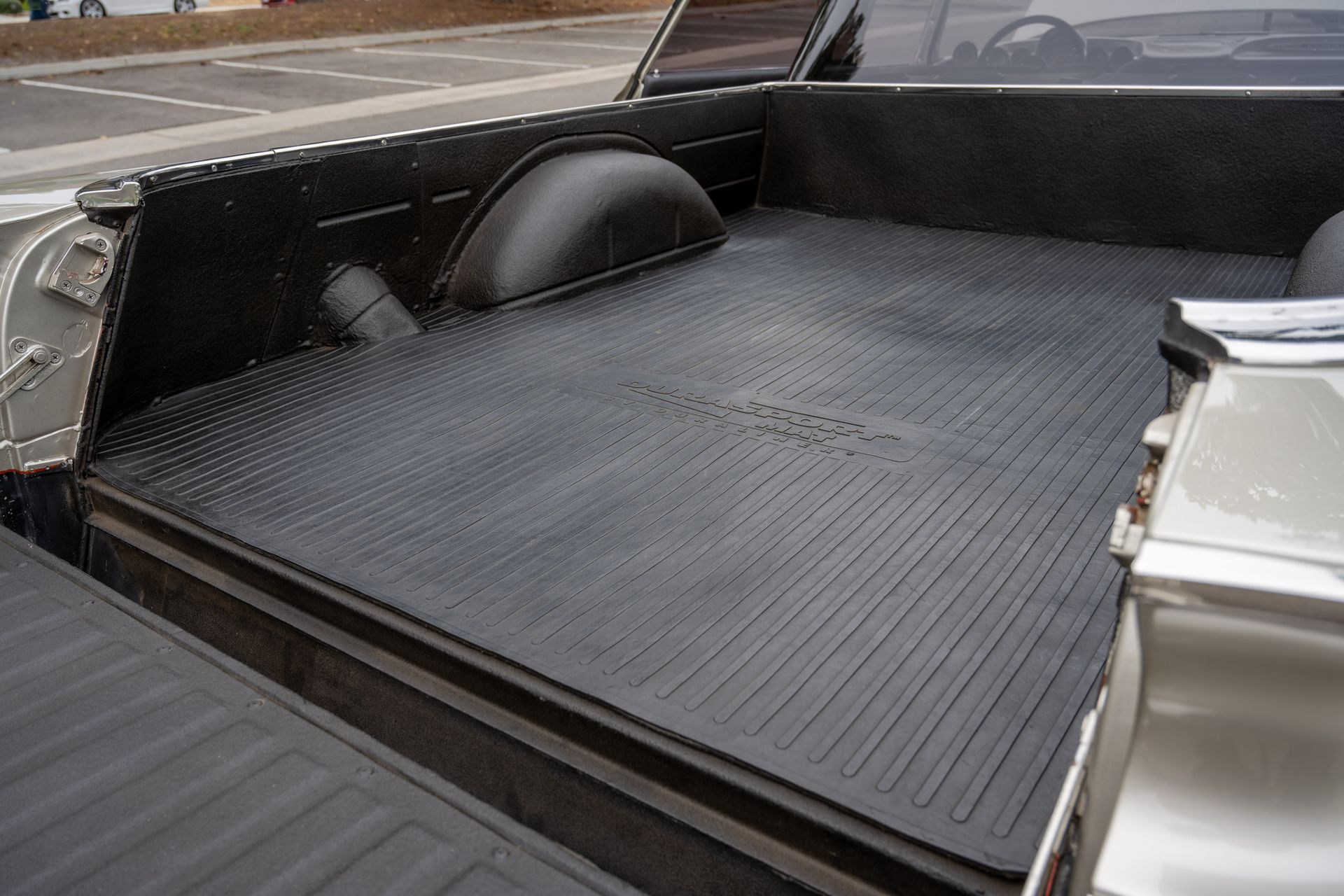 A truck bed with a black rubber mat on it