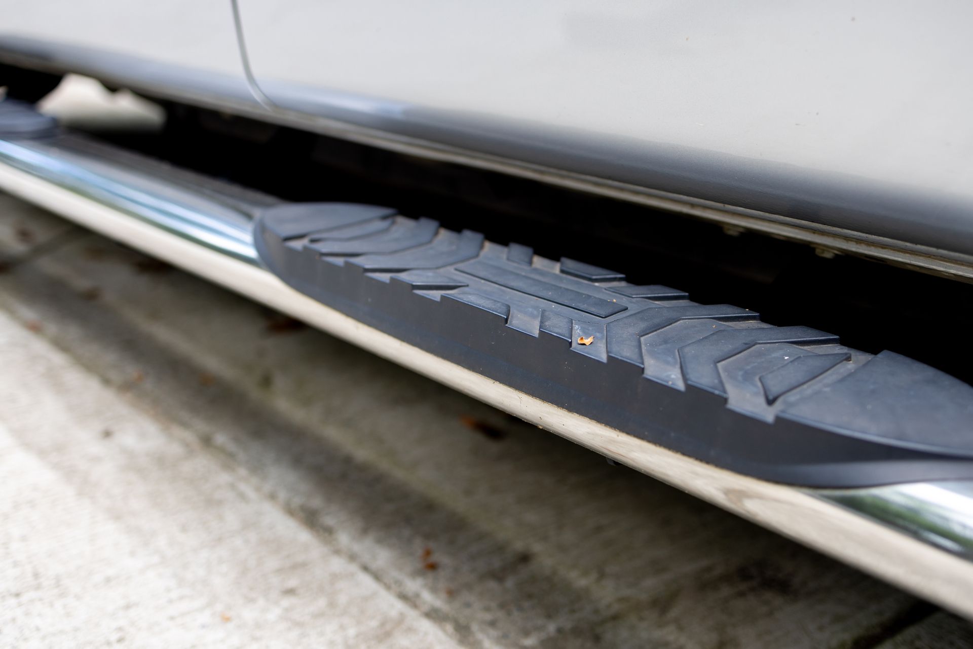 A close up of a side step on a silver truck.